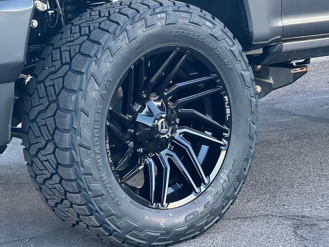 A close up of a tire on a truck with black wheels.