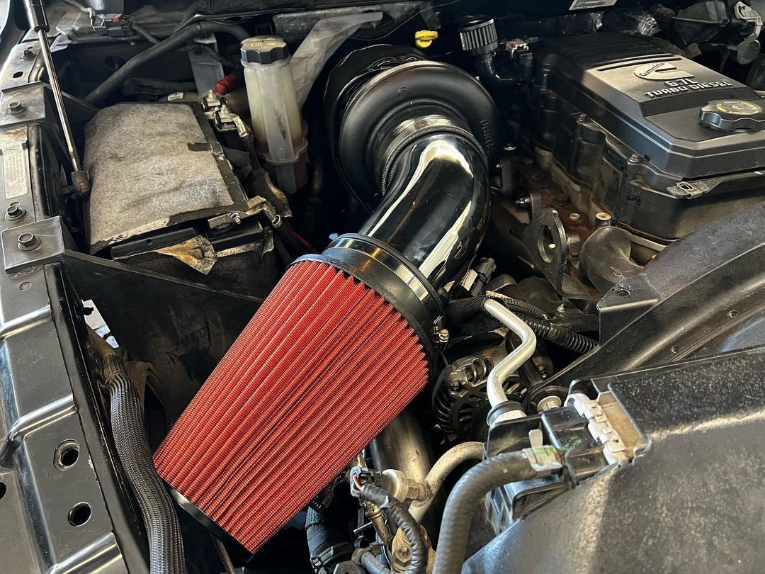 A close up of a car engine with a red air filter.