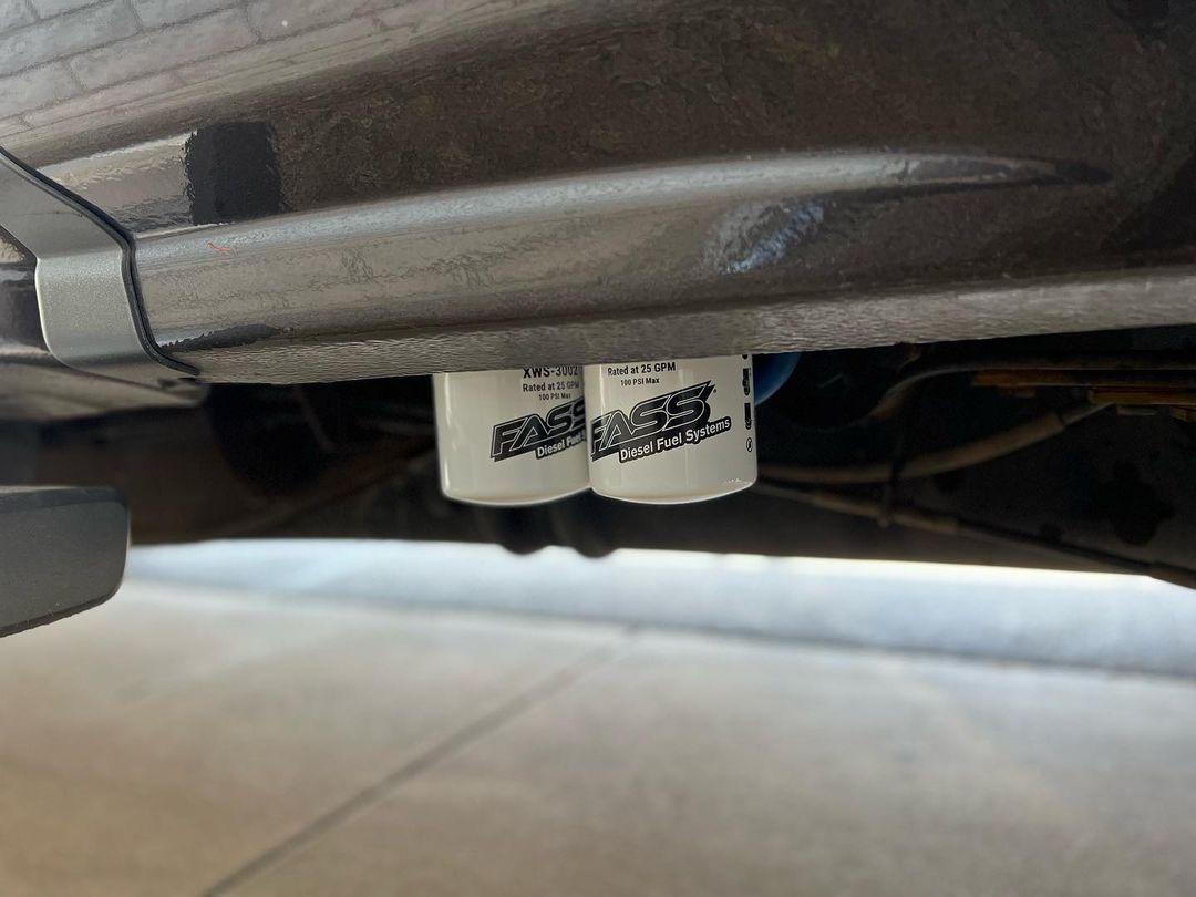 A close up of a fuel filter on the underside of a car.