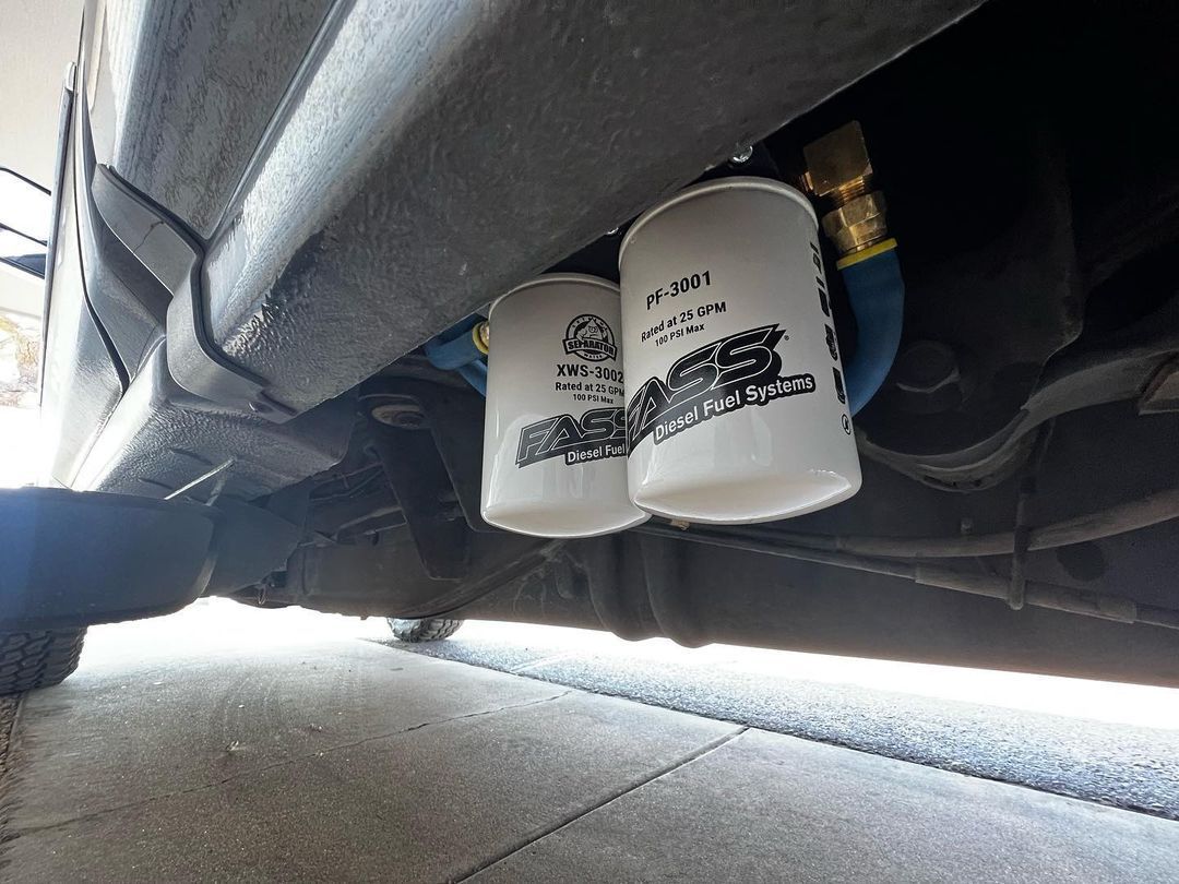 Two oil filters are hanging from the underside of a car.