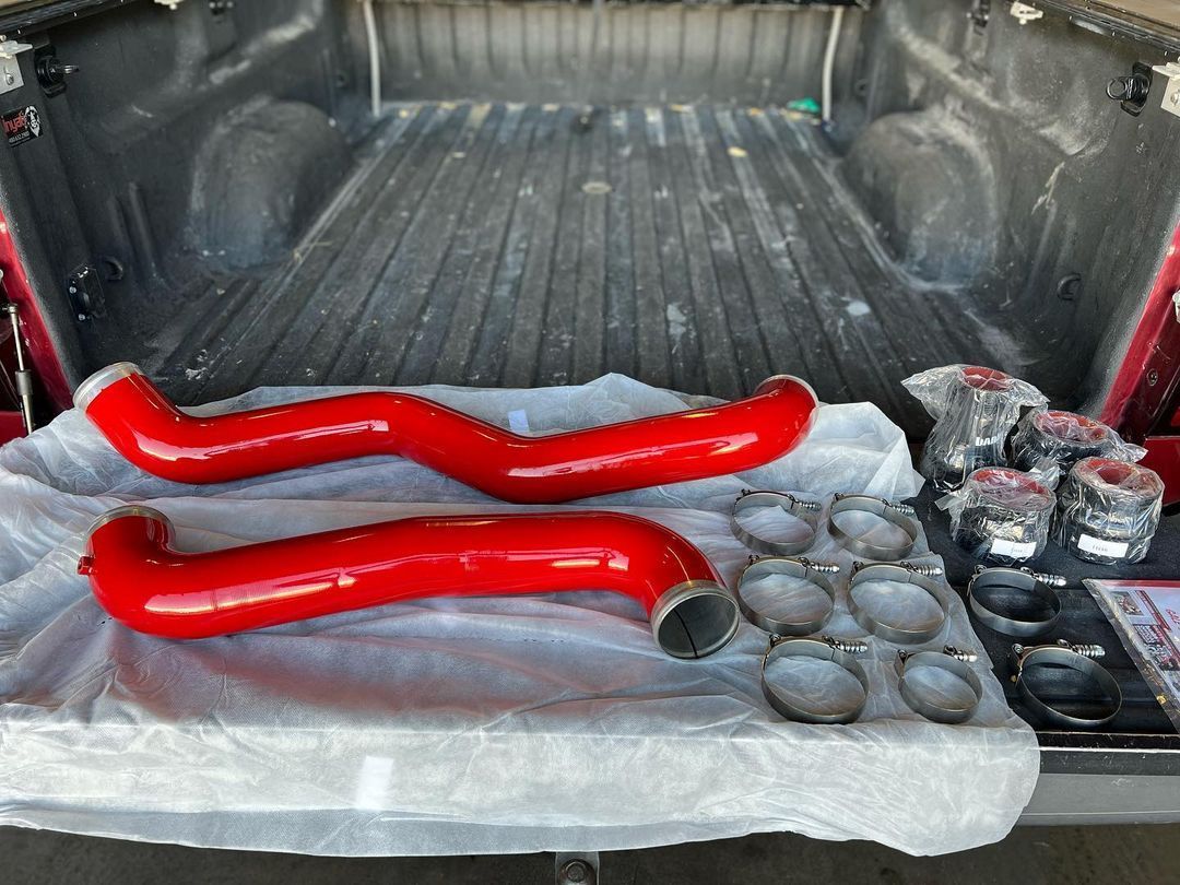 Two red pipes are sitting in the back of a truck.