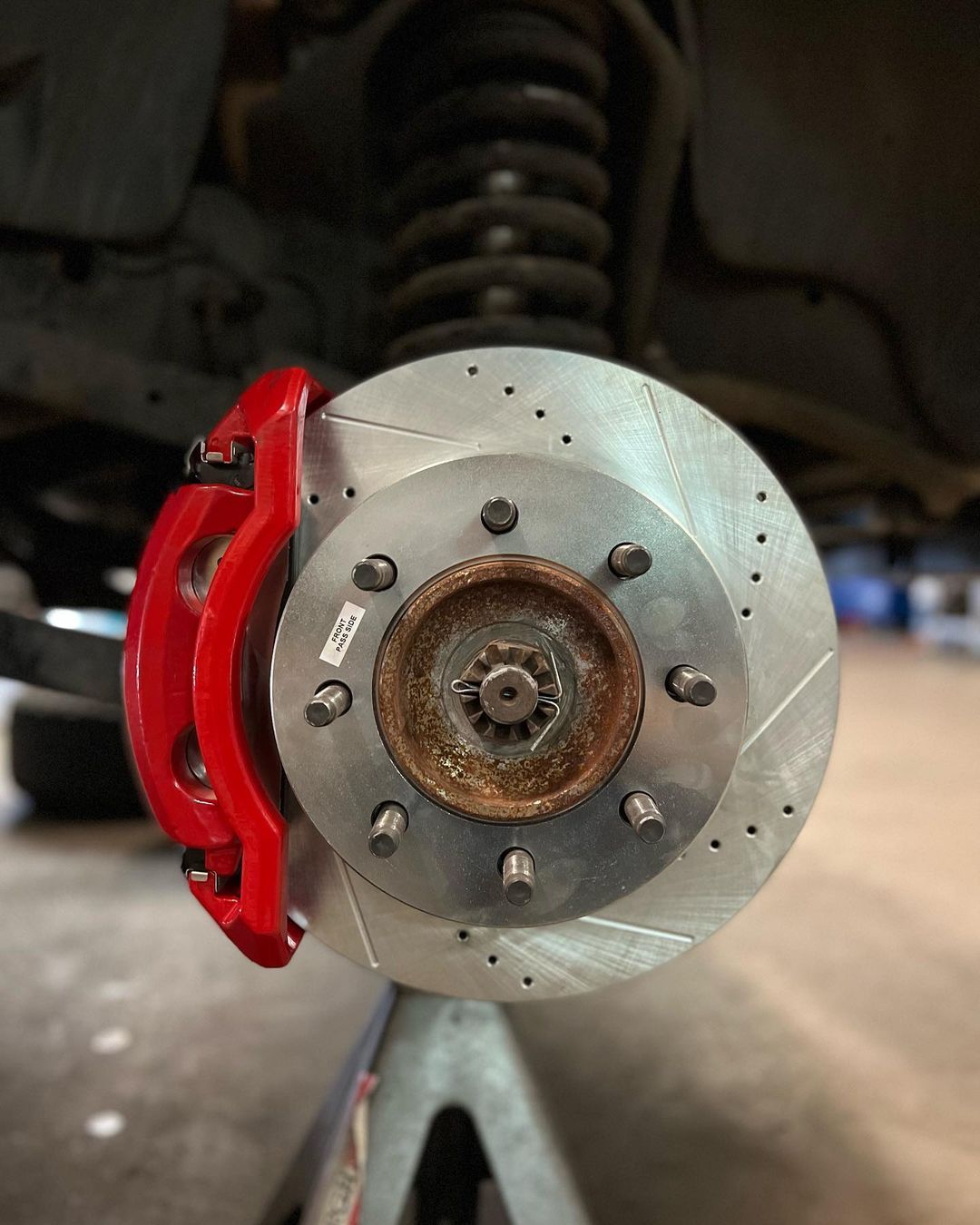 A close up of a brake disc on a car with a red brake caliper