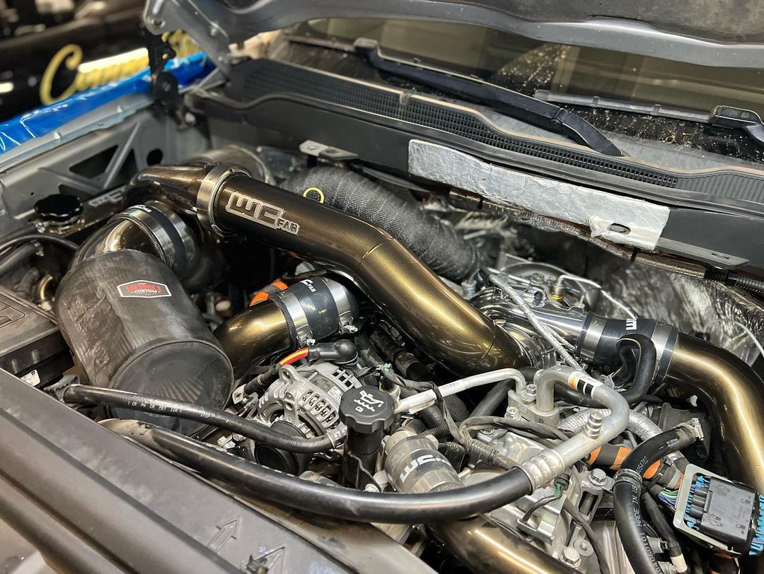 A close up of a car engine with a hood open.