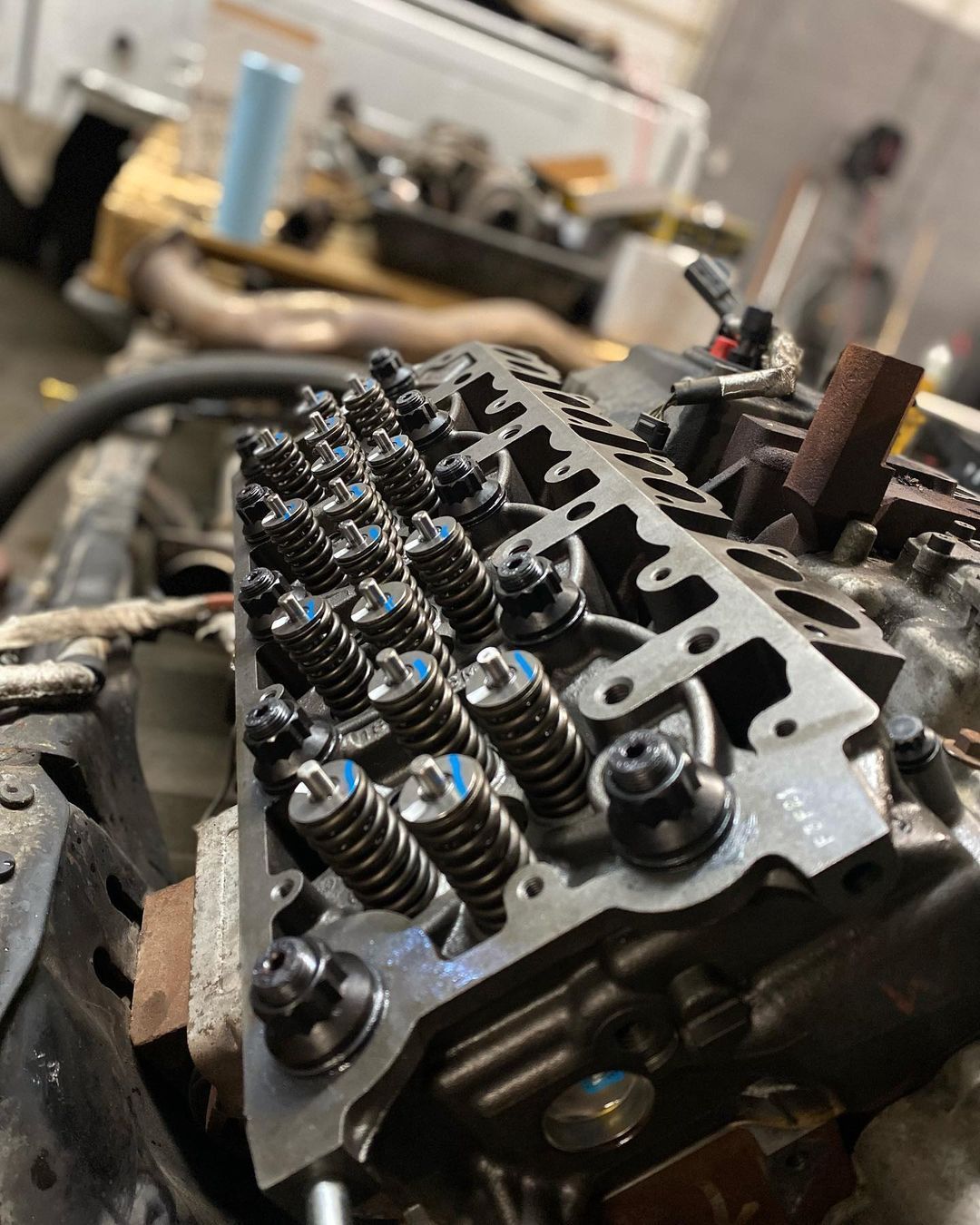 A close up of a cylinder head of a car engine in a garage.