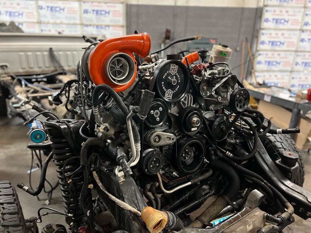 A large engine with a turbocharger attached to it is being worked on in a garage.