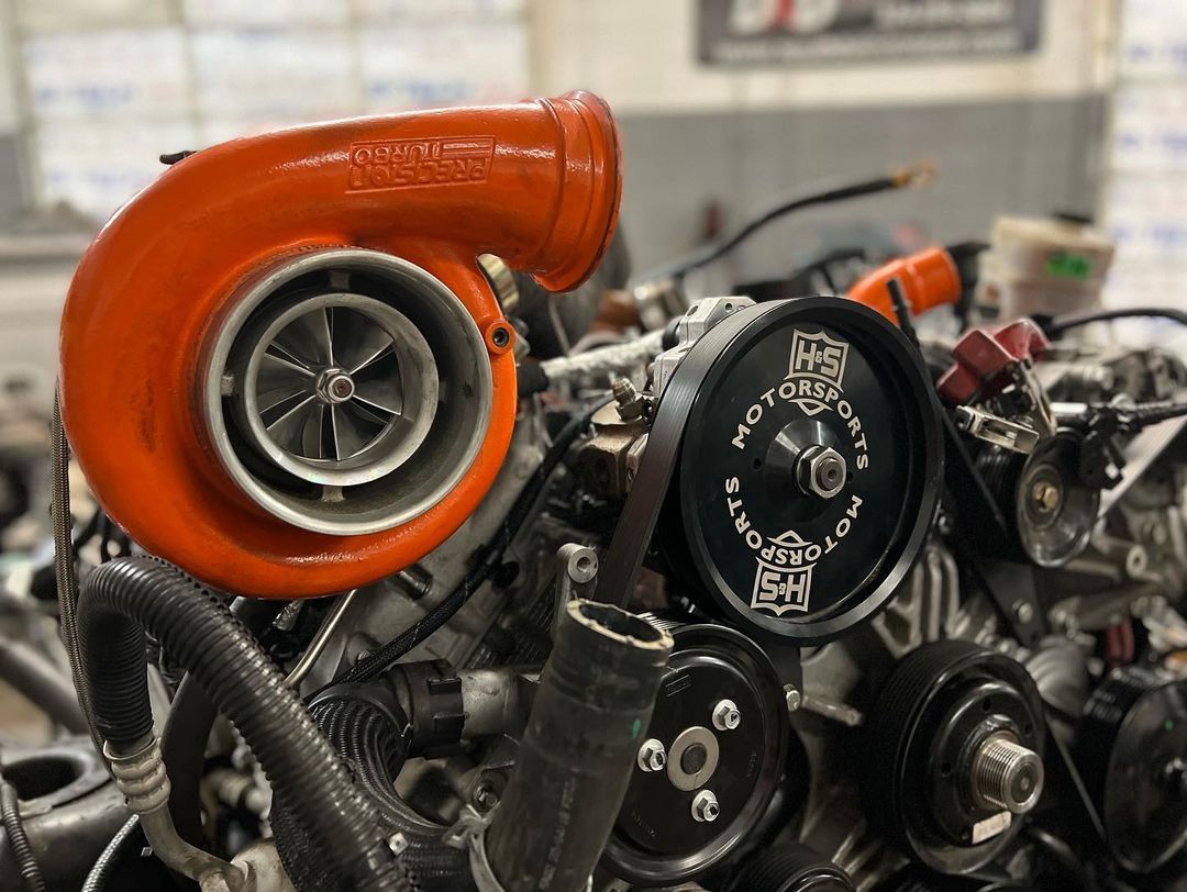 A turbocharger is sitting on top of a car engine.