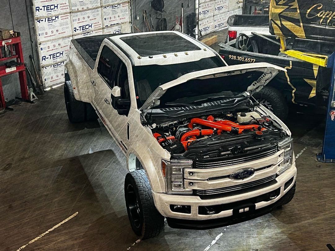 A white truck with the hood open is parked in a garage.