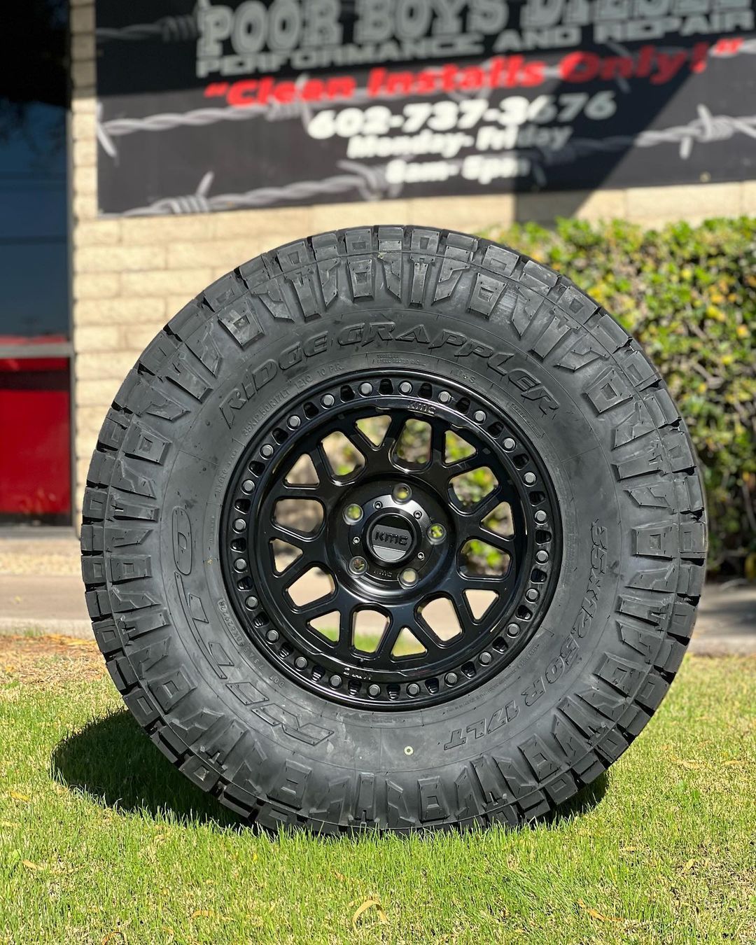 A tire and wheel are sitting on the grass in front of a building.