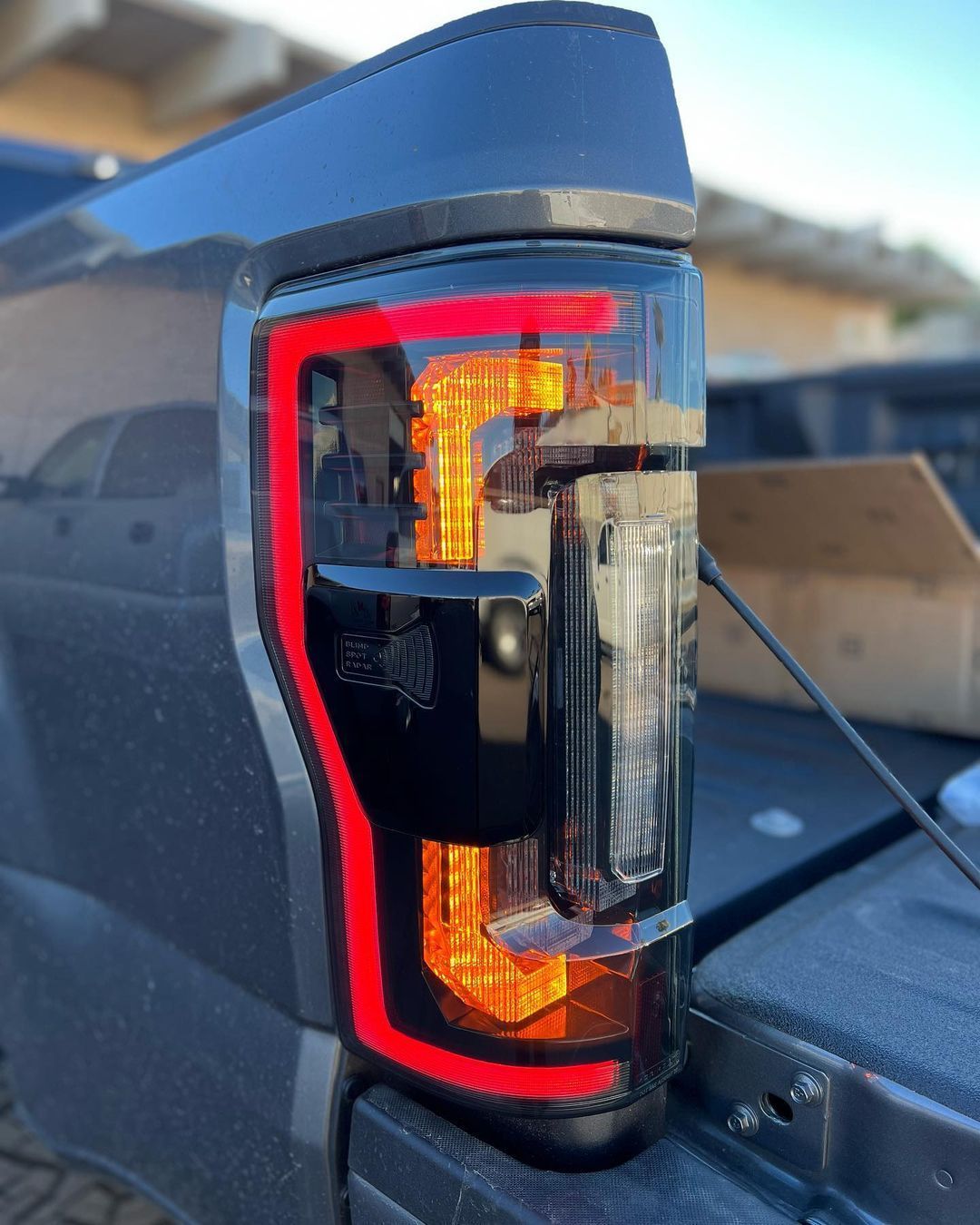 A black truck with a red tail light is parked in front of a house.