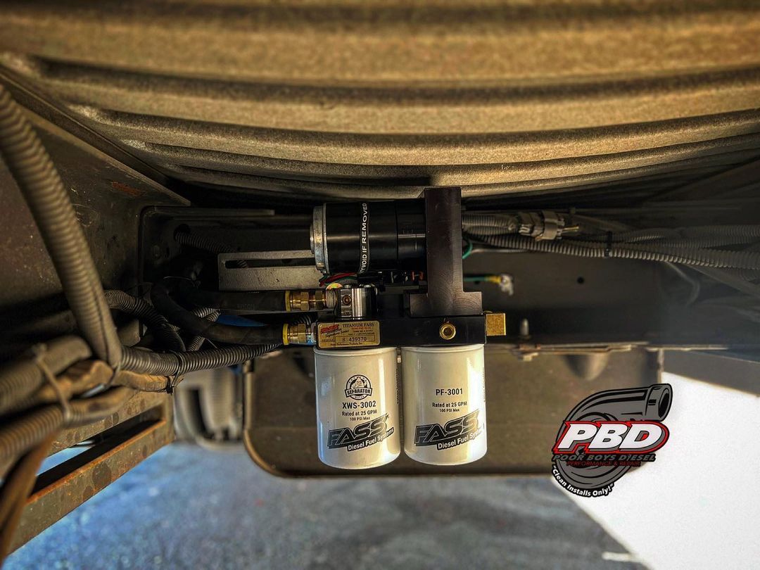 A close up of a fuel filter on the underside of a car.