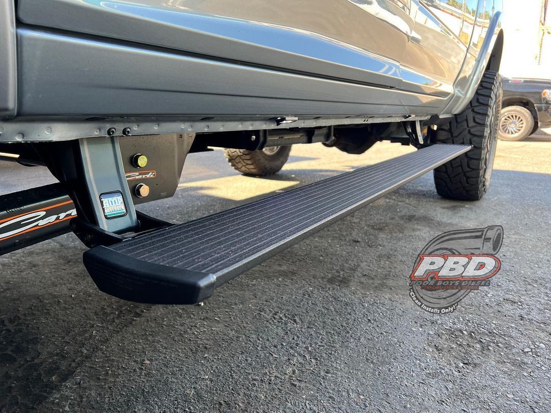 A truck with a side step is parked on the side of the road.