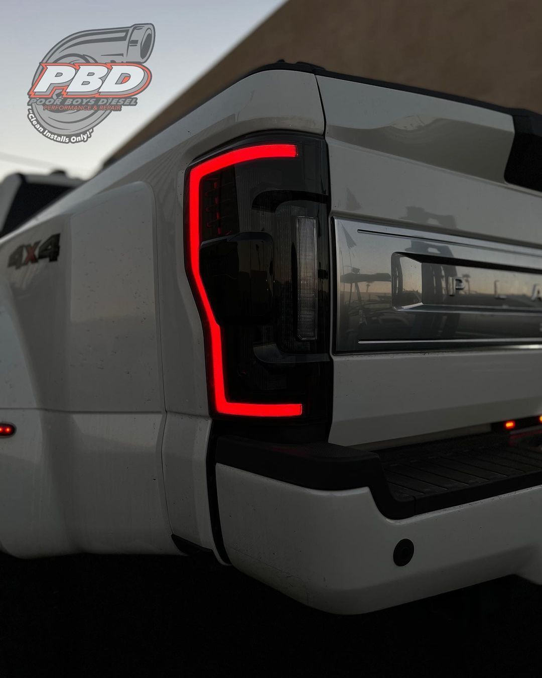 A white truck with a red tail light and a pbd logo