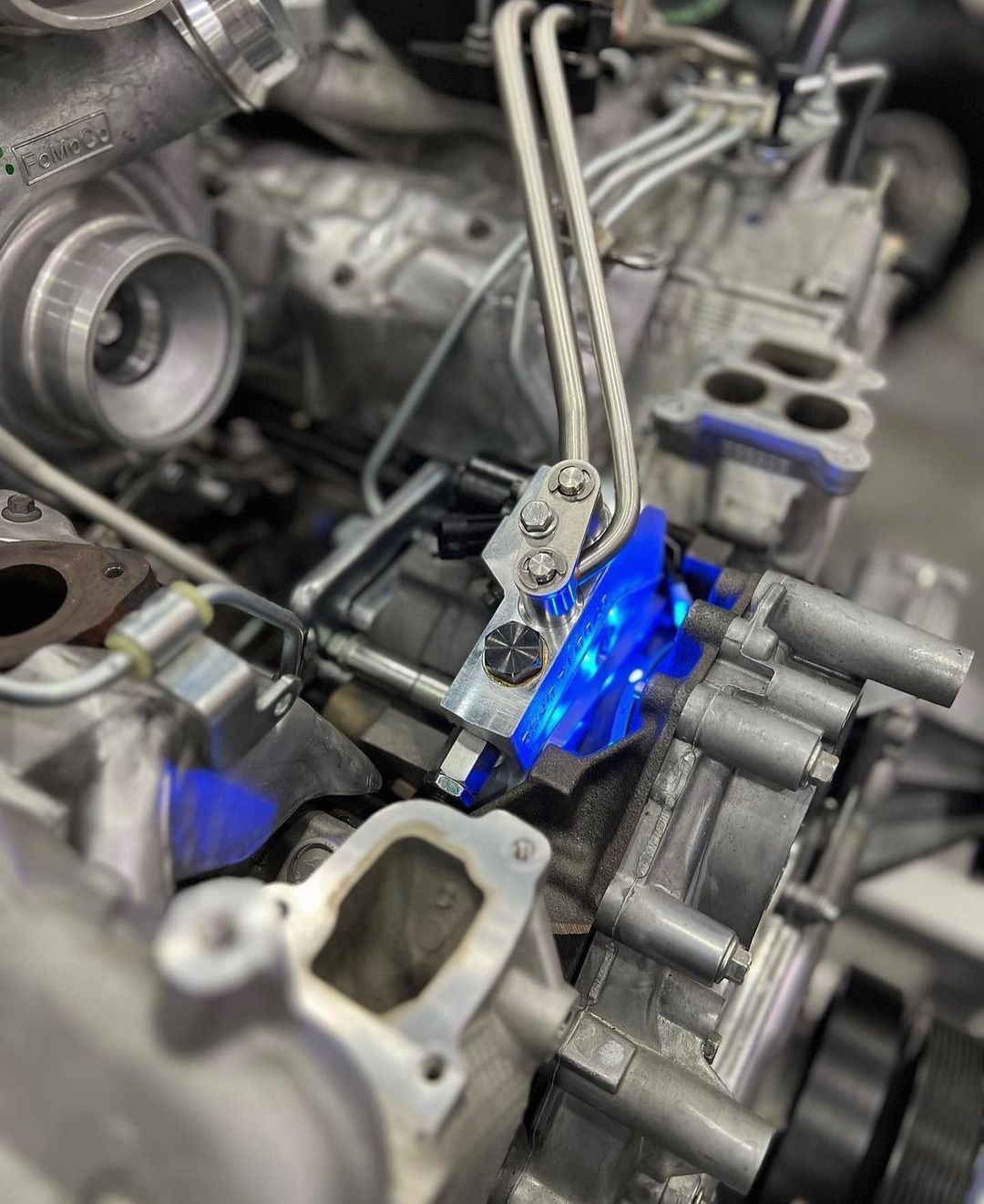 A close up of a car engine with a blue light on it.