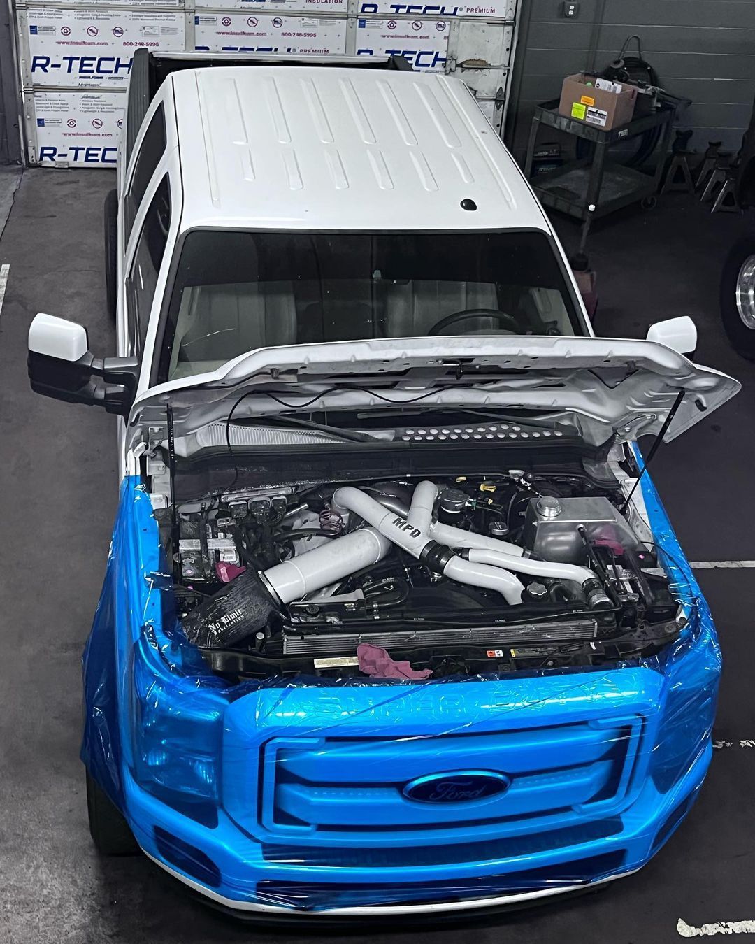 A blue and white ford truck with the hood open