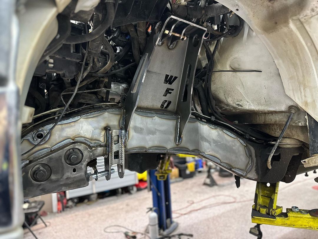 A car is being worked on on a lift in a garage.