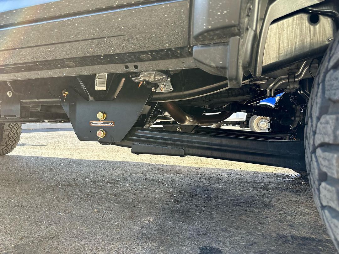 A close up of the underside of a truck parked on the side of the road.