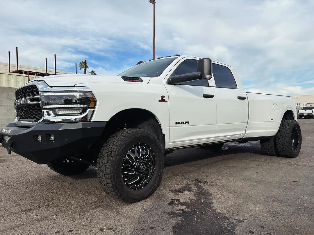 A white ram truck is parked in a parking lot.