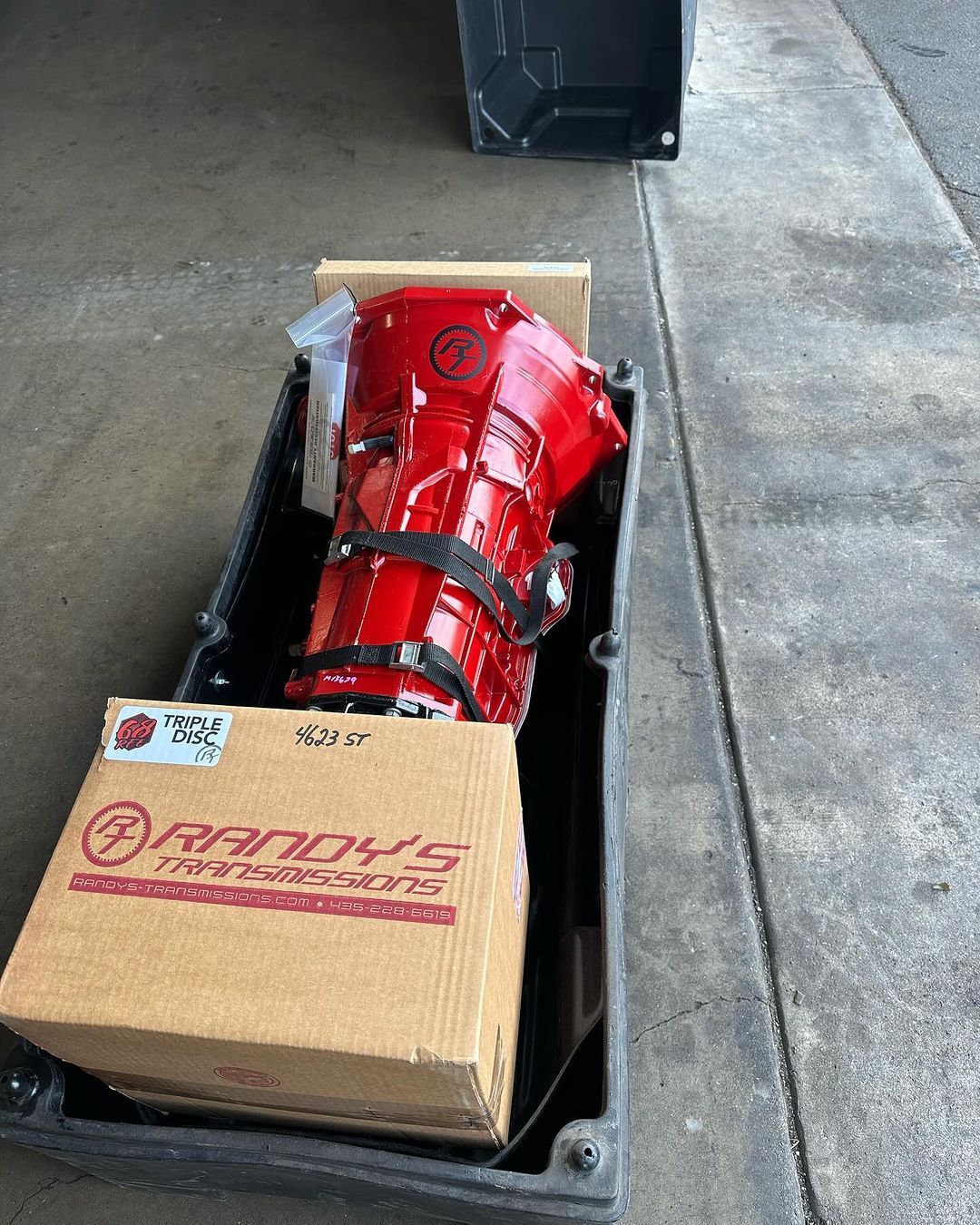 A red gearbox is sitting in a box on the sidewalk.