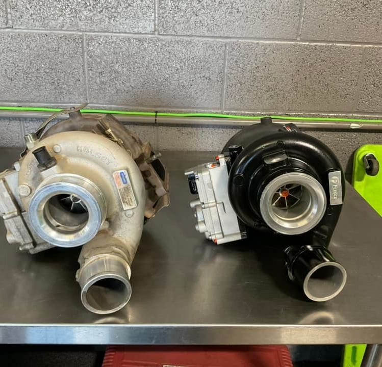 Two turbochargers are sitting on a stainless steel table