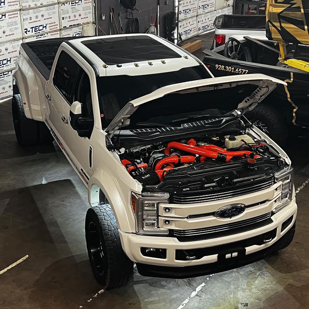 A white truck with the hood open is parked in a garage.