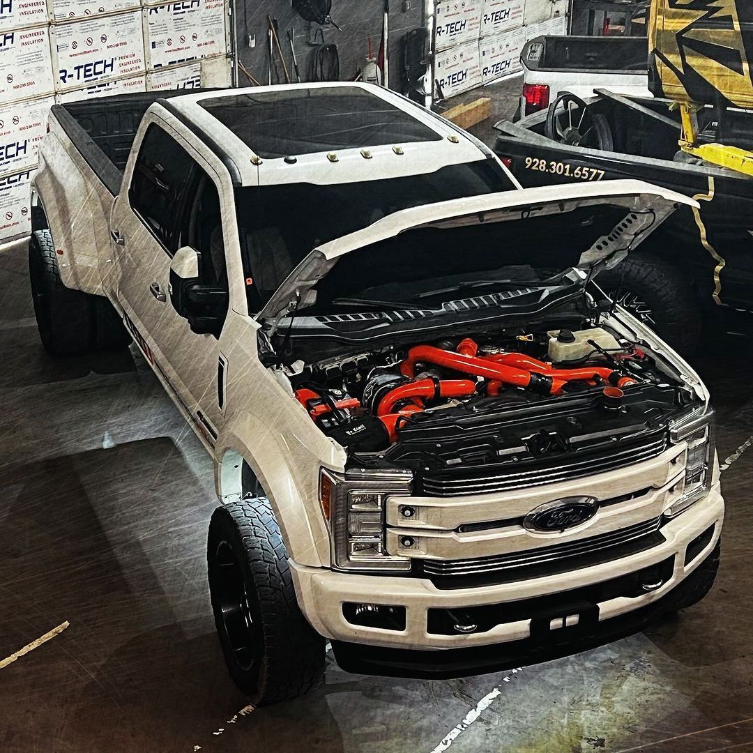 A white truck with the hood open is parked in a garage.