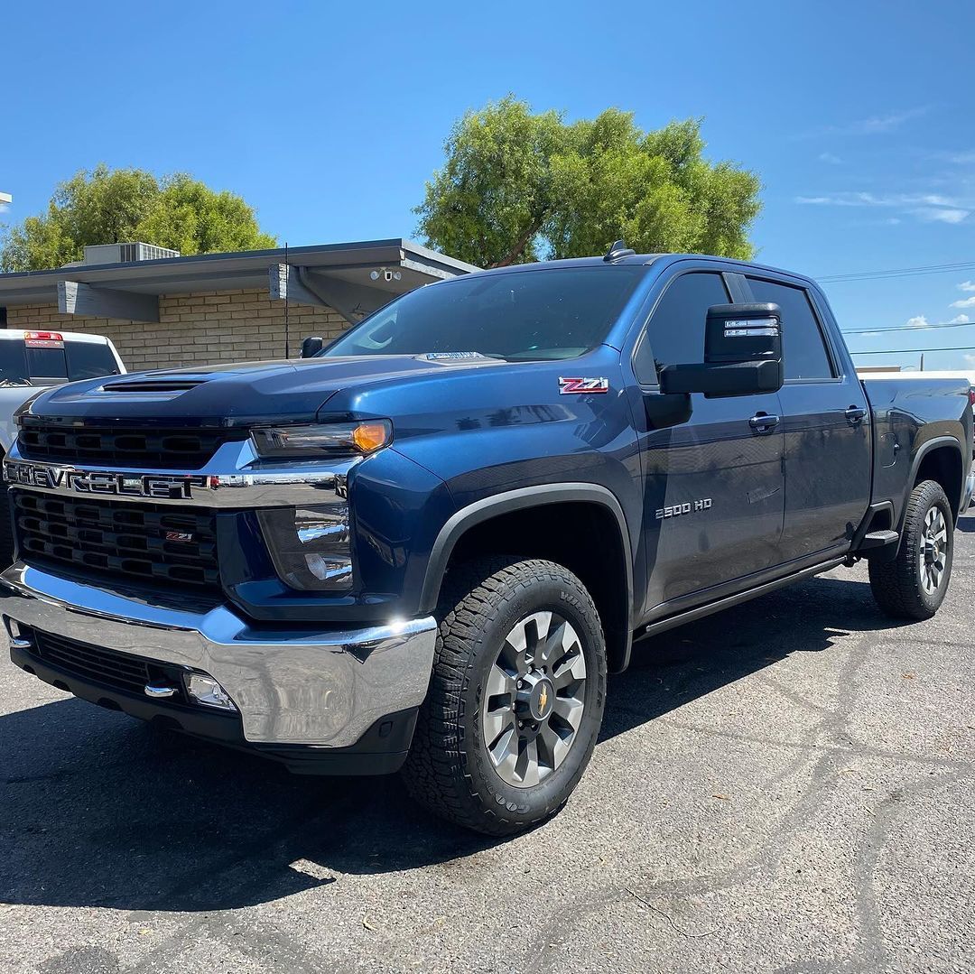 A blue truck is parked in a parking lot on a sunny day.