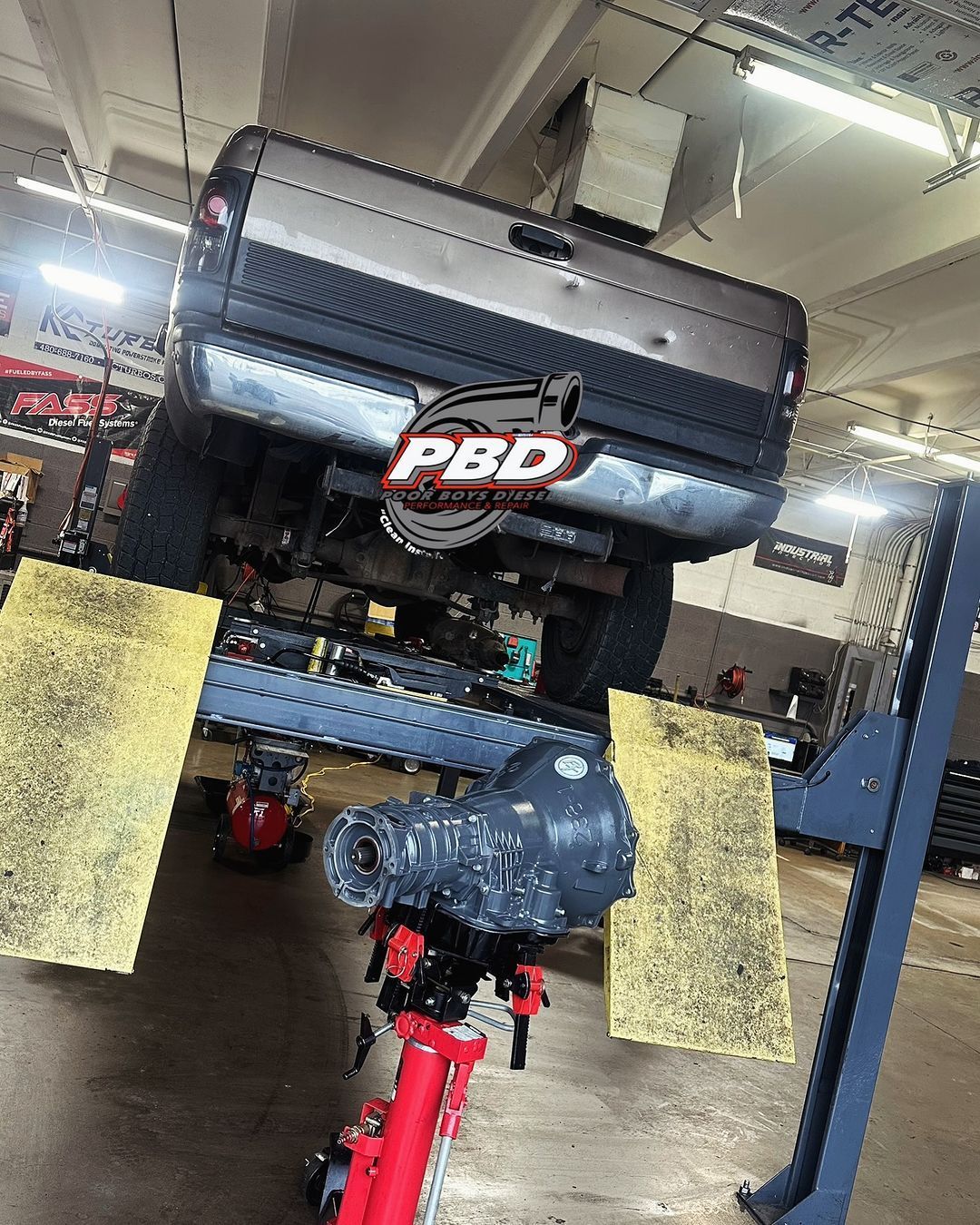 A truck is sitting on a lift in a garage.