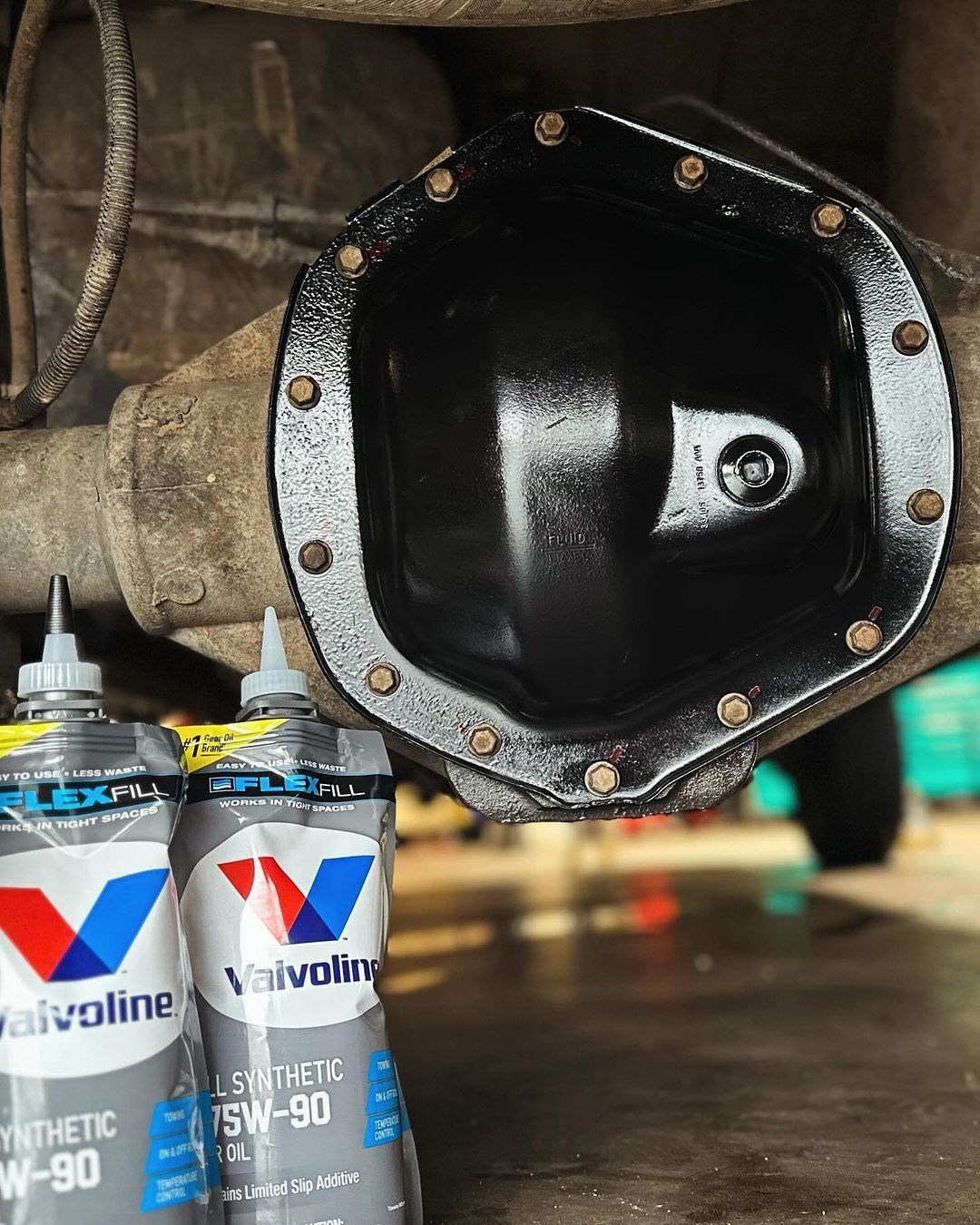 Two bottles of valvoline oil are sitting under a car