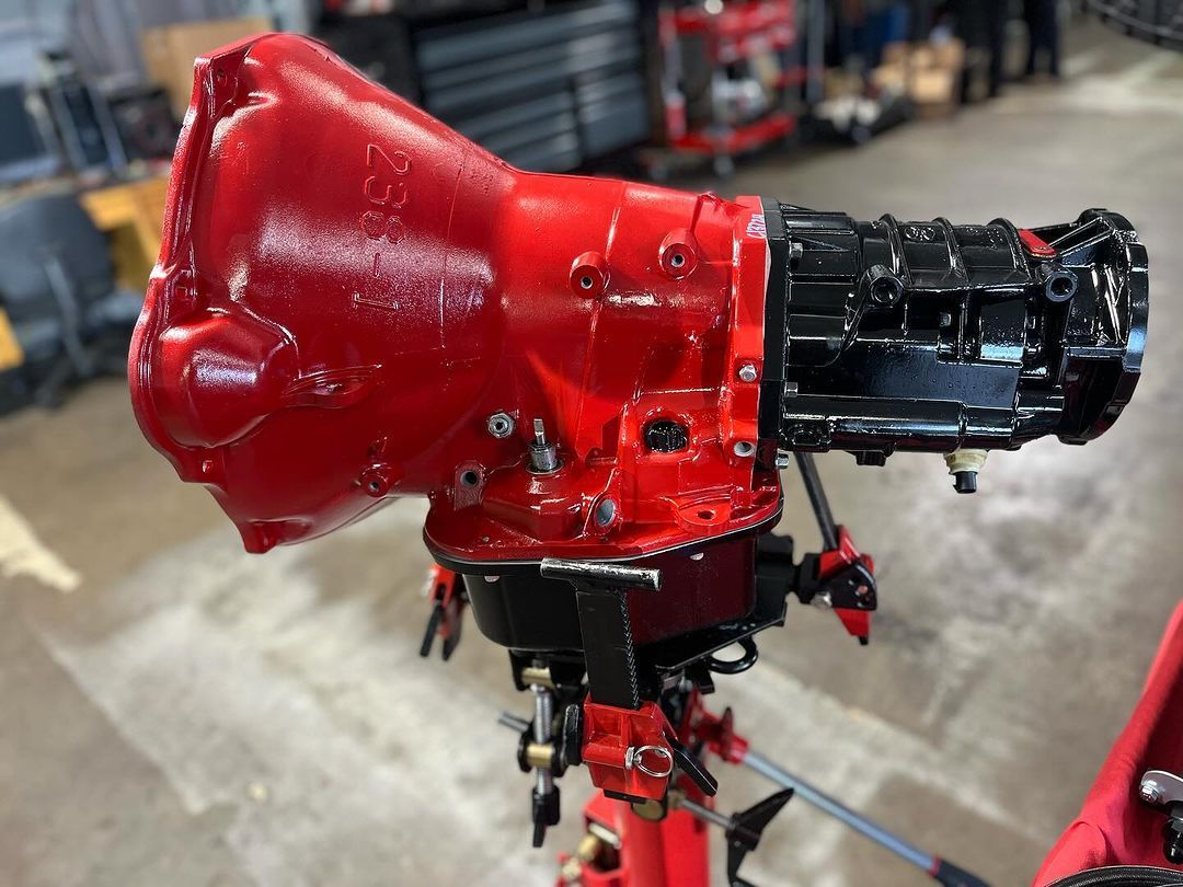 A red and black gearbox is sitting on a stand in a garage.