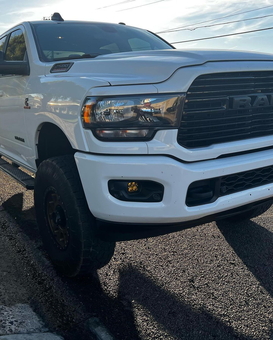 A white ram truck is parked on the side of the road.