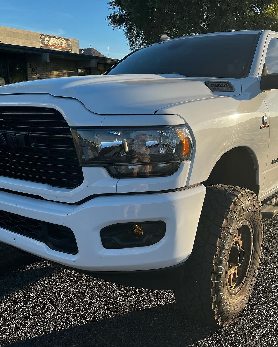 A white ram truck is parked on the side of the road.
