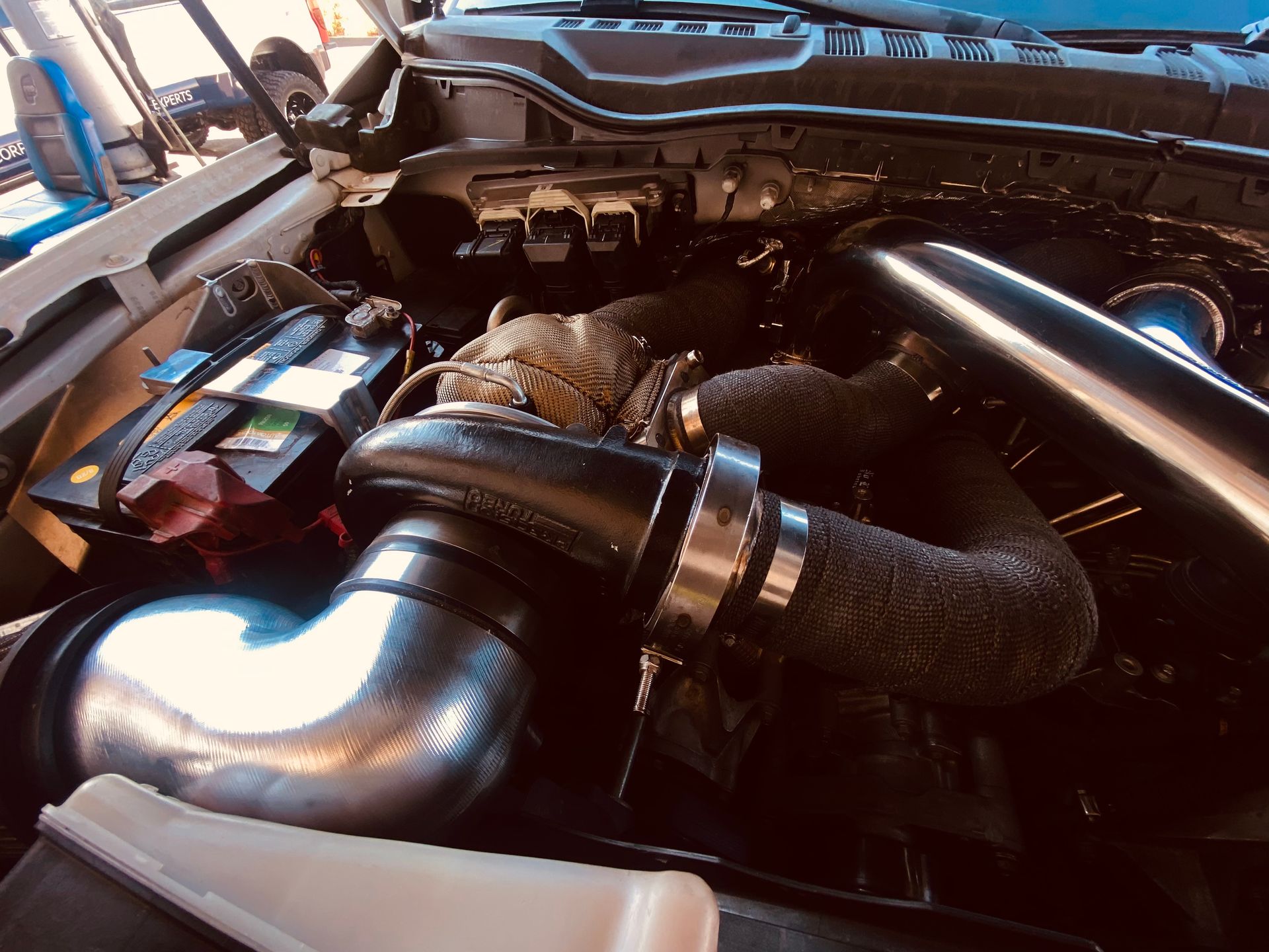 A close up of a car engine with the hood open