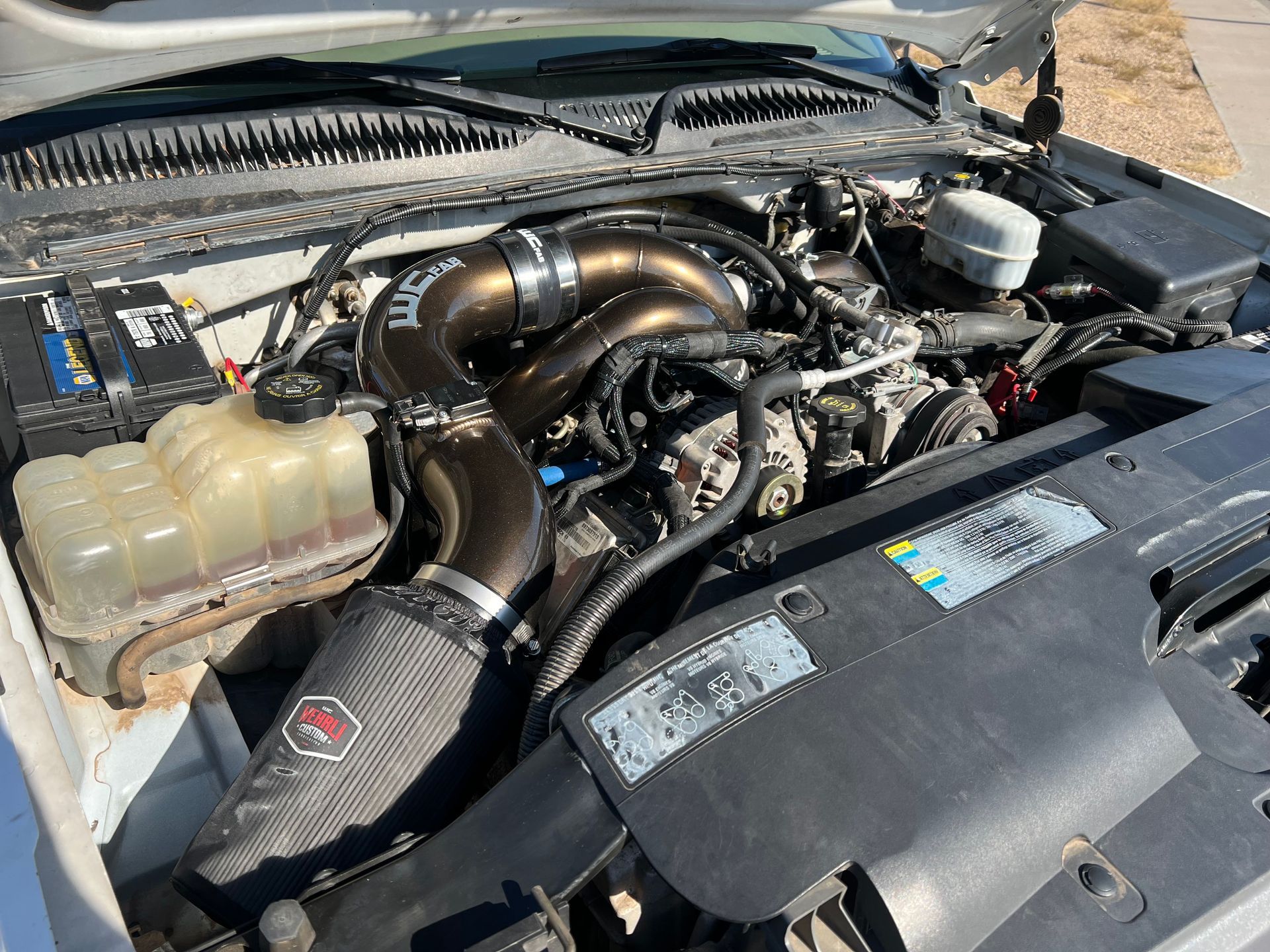 A close up of a car engine with the hood open