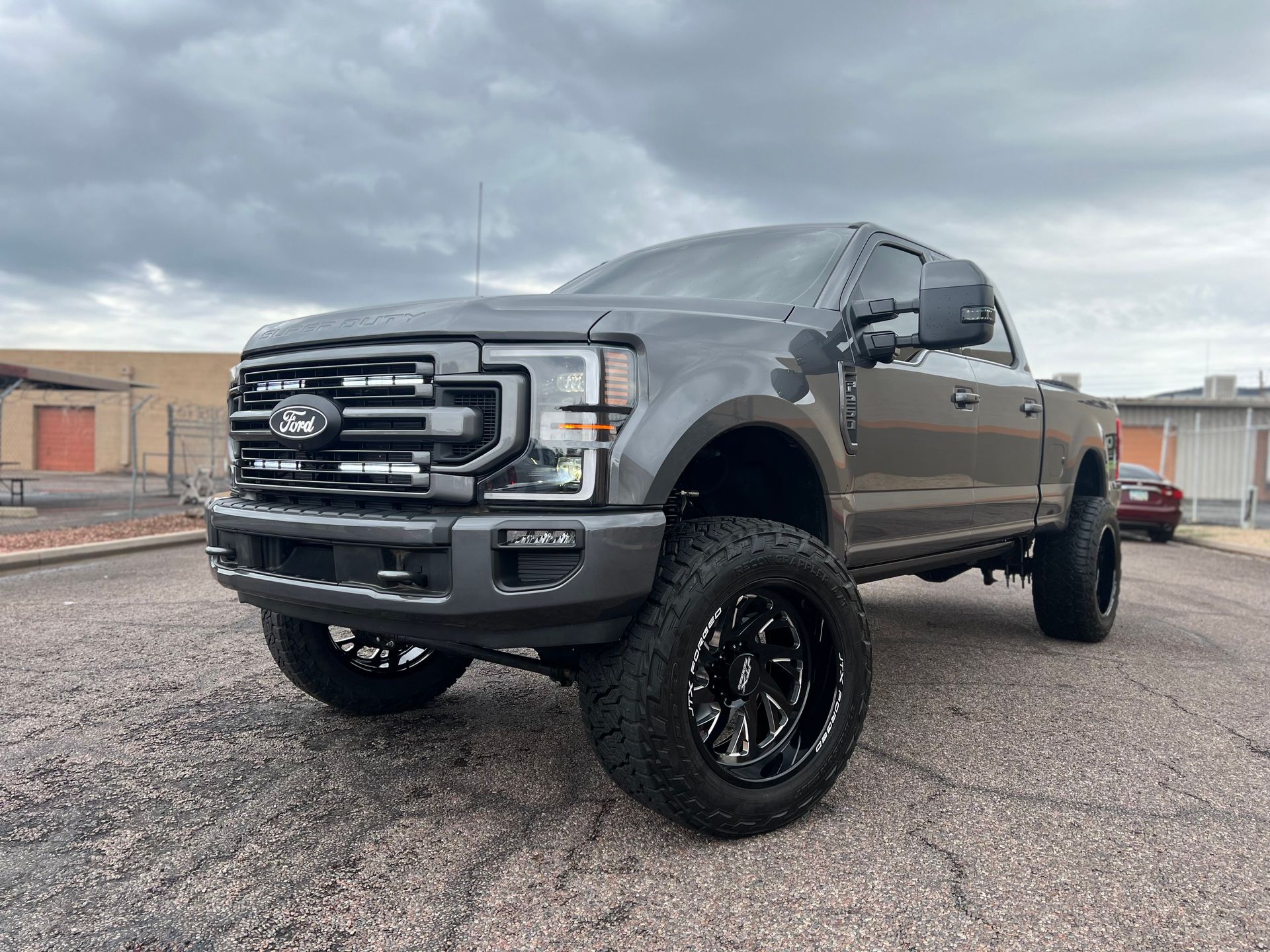 A gray ford f250 super duty truck is parked on a gravel road.