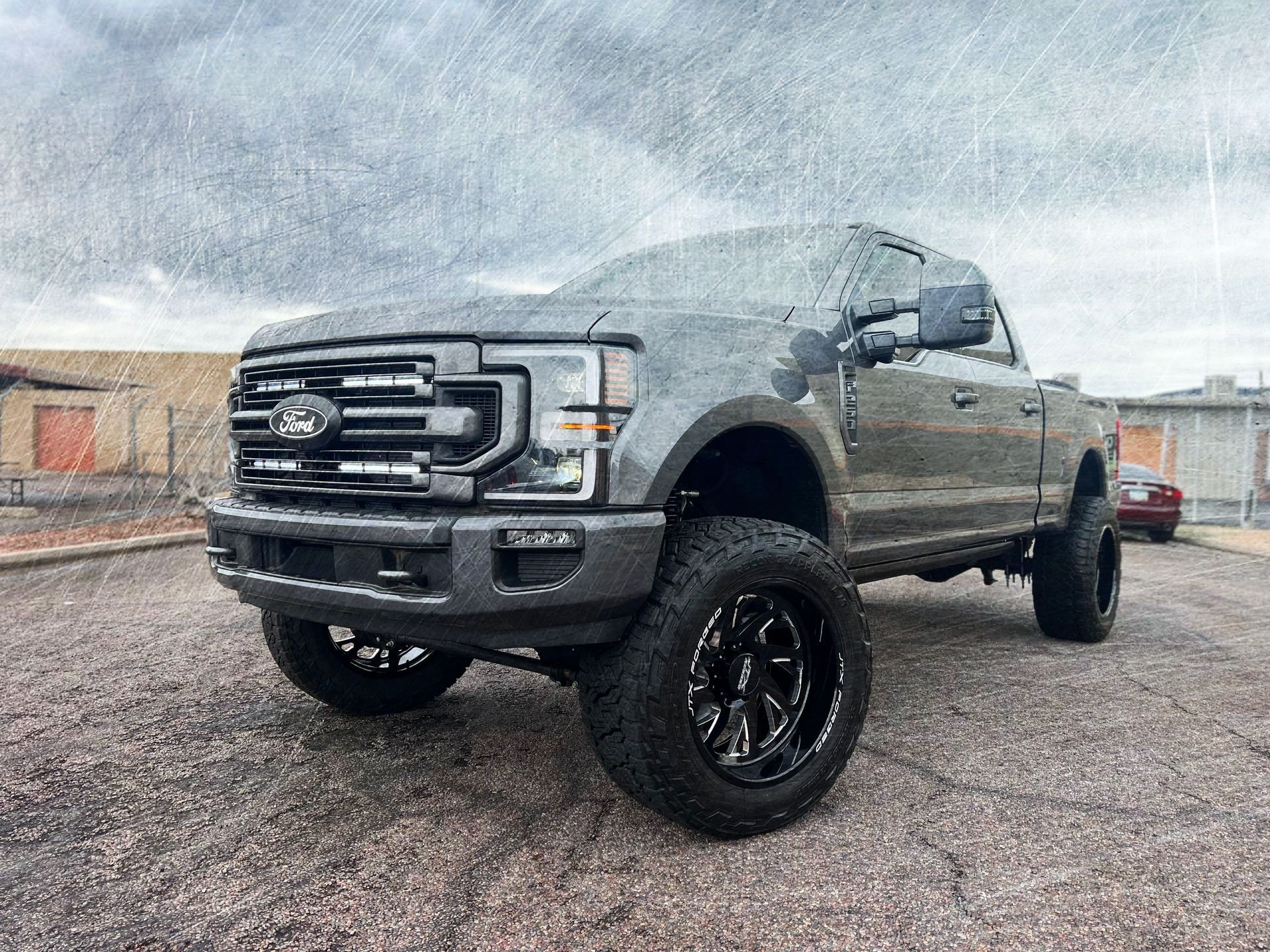 A ford truck is parked on a gravel road in front of a building.