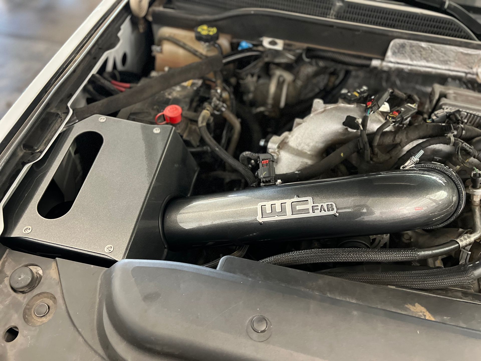 A close up of the engine of a car with the hood open.