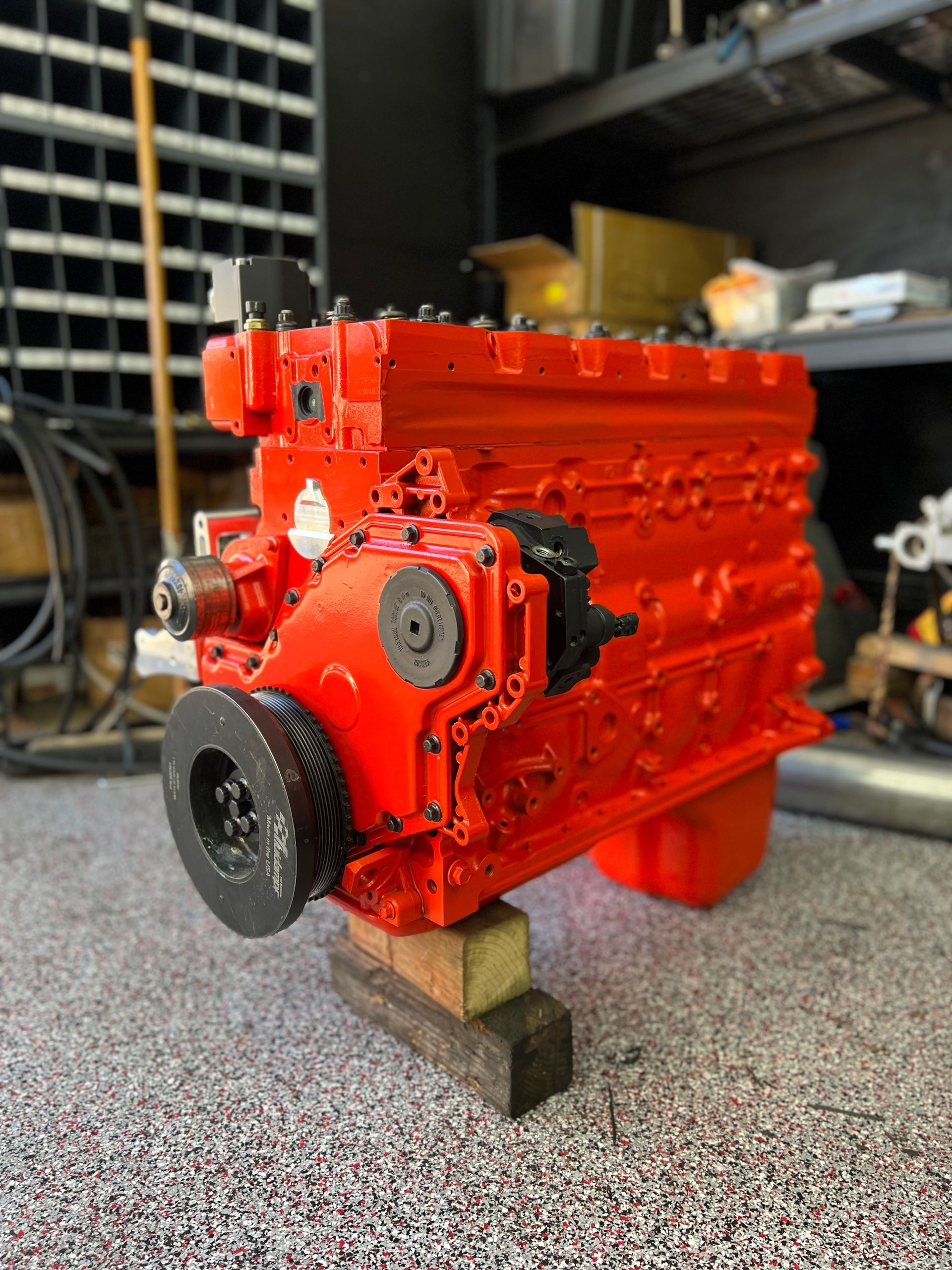 A red engine is sitting on a wooden block in a garage.