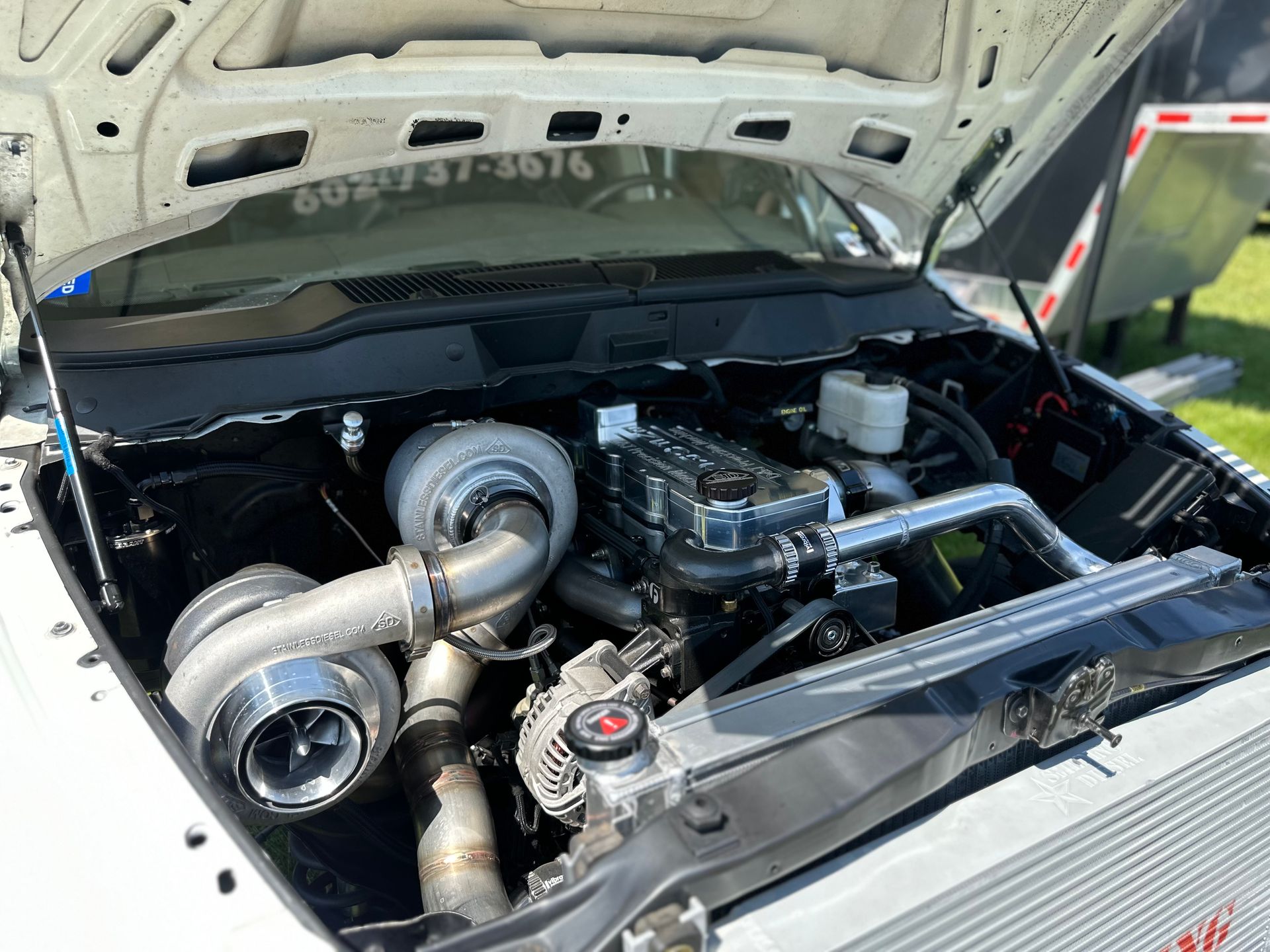 The engine of a white truck with the hood open is shown.