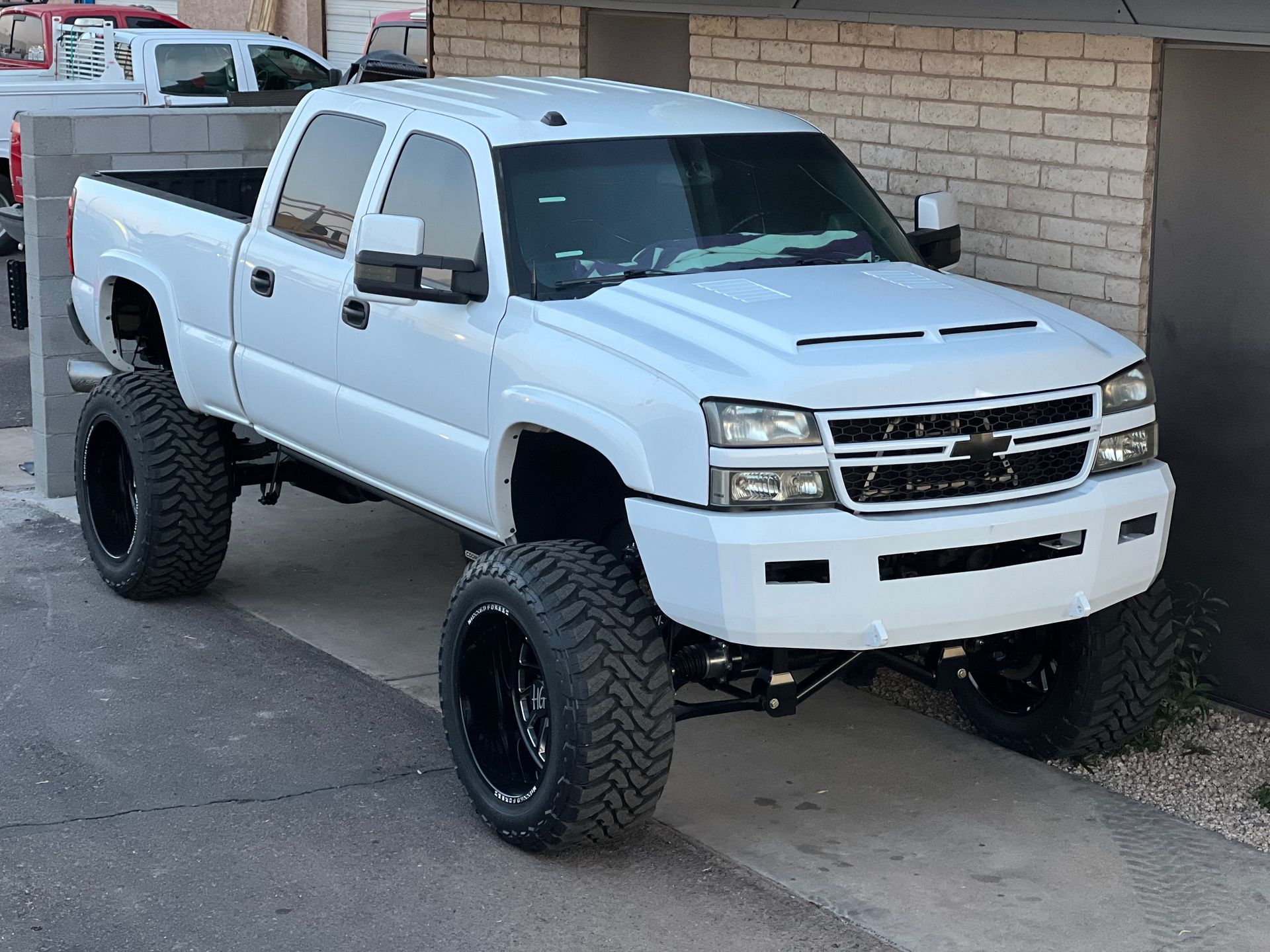 A white truck is parked in front of a brick building.