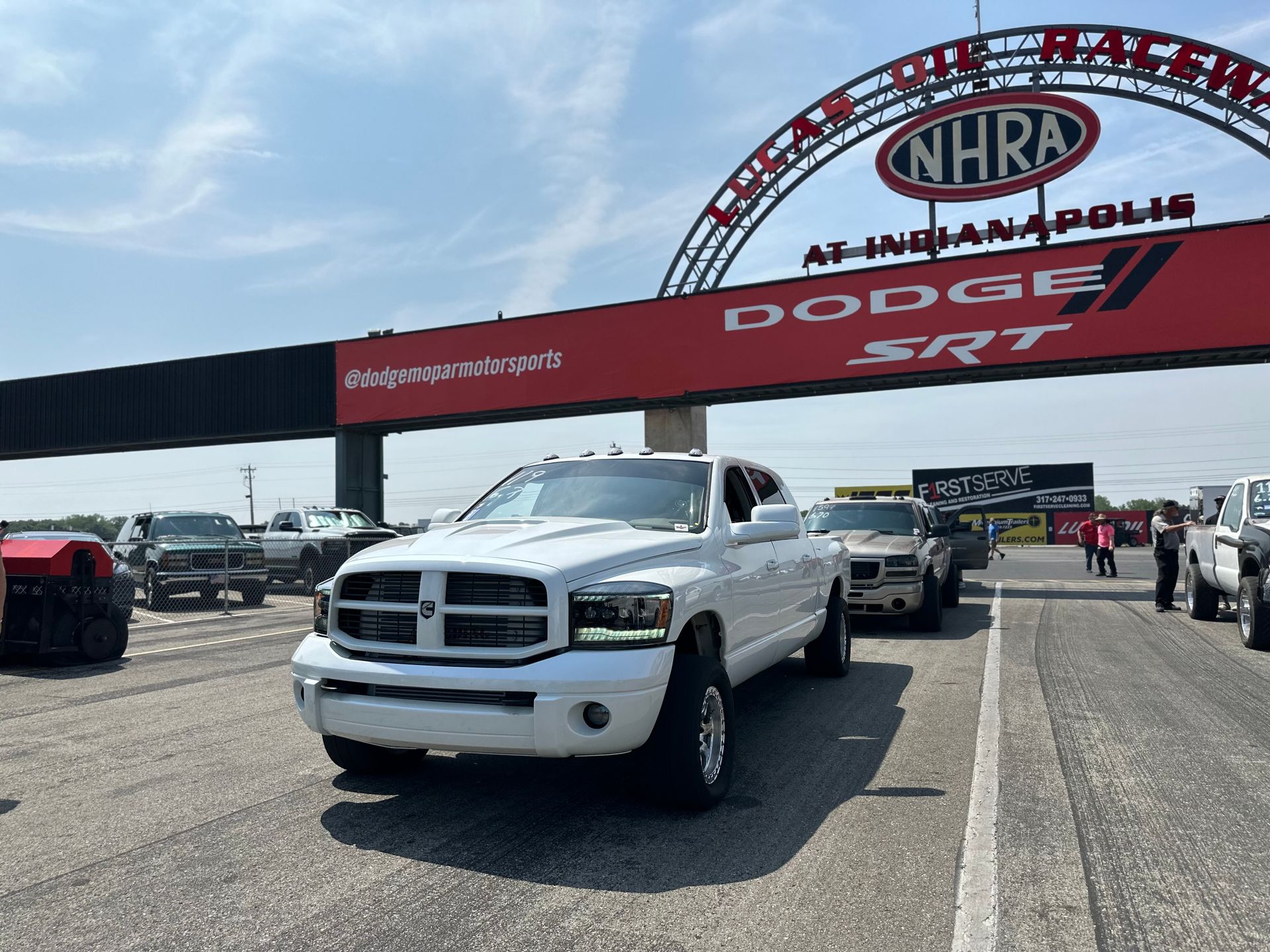 A white truck is parked in front of a sign that says dodge srt