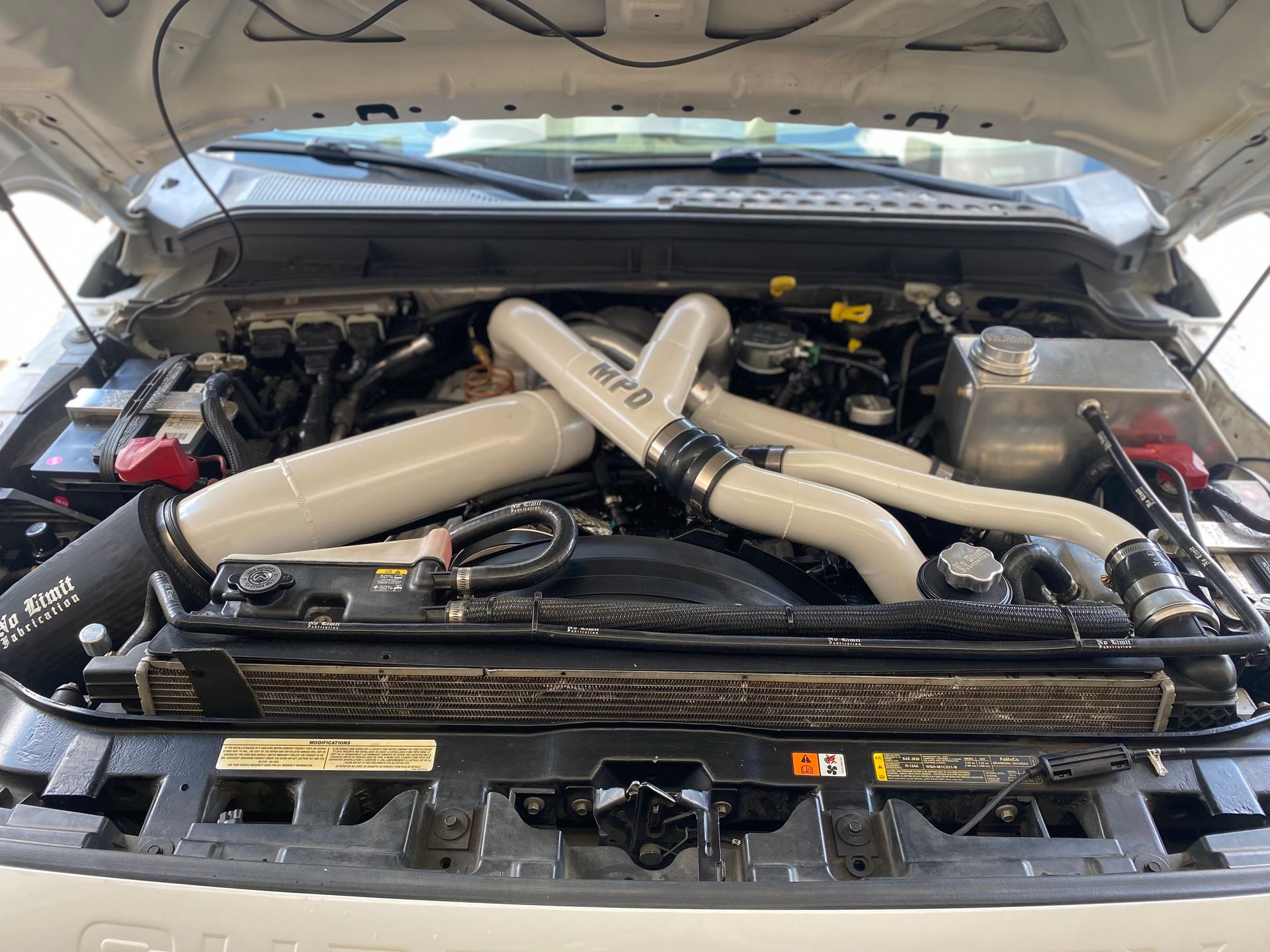 The engine of a white truck is shown with the hood open.