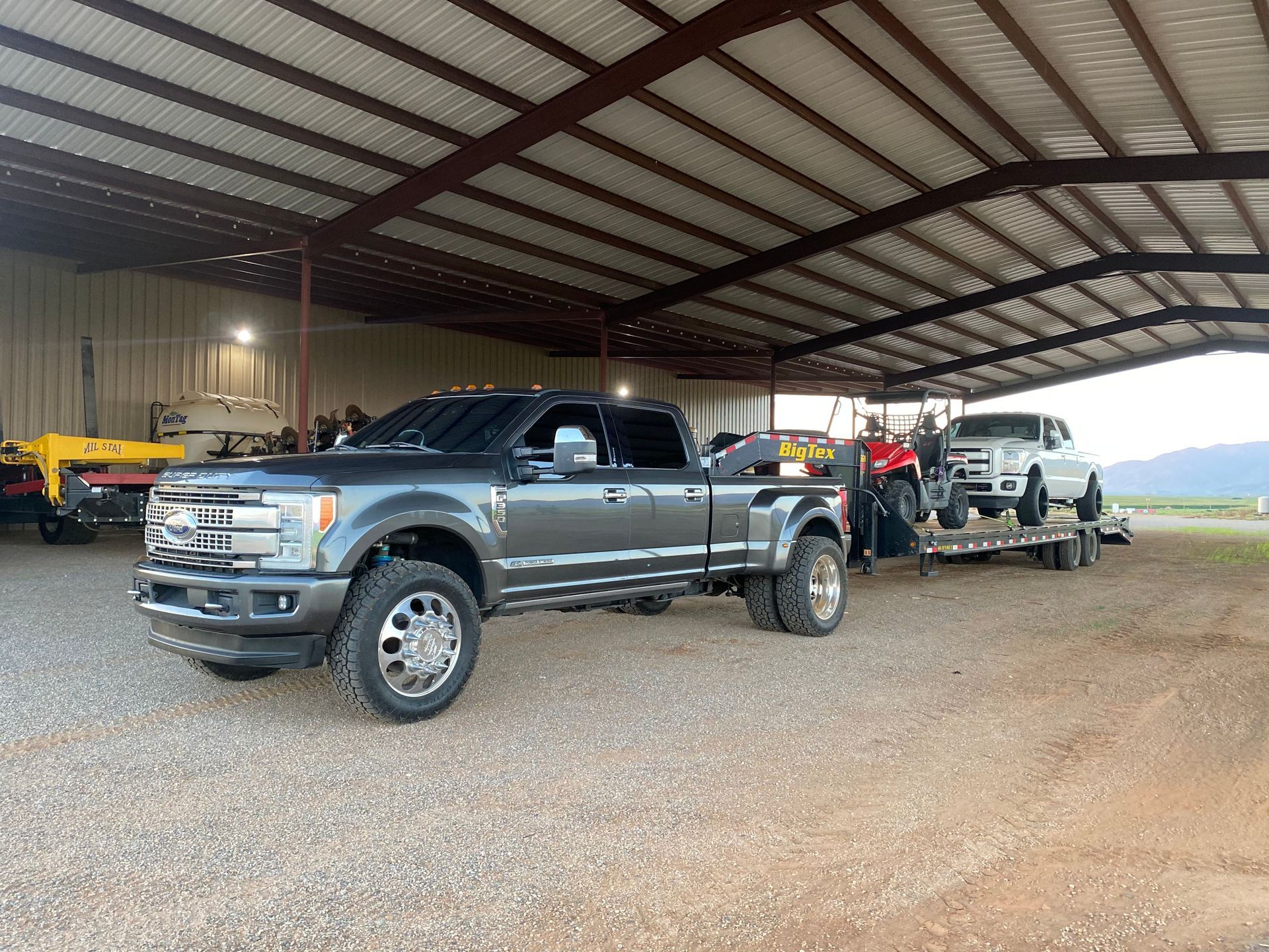 A truck is towing a trailer with a jeep on it.