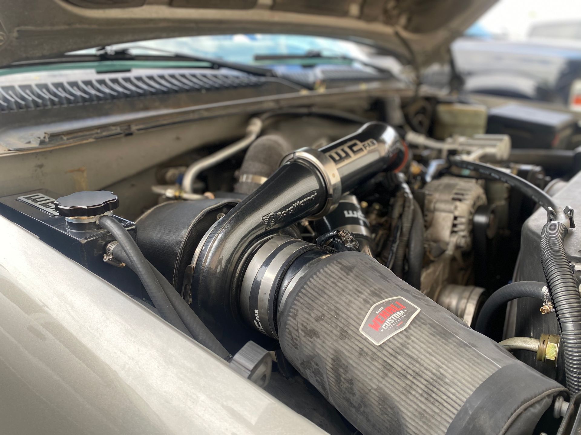 A close up of a car engine with the hood open