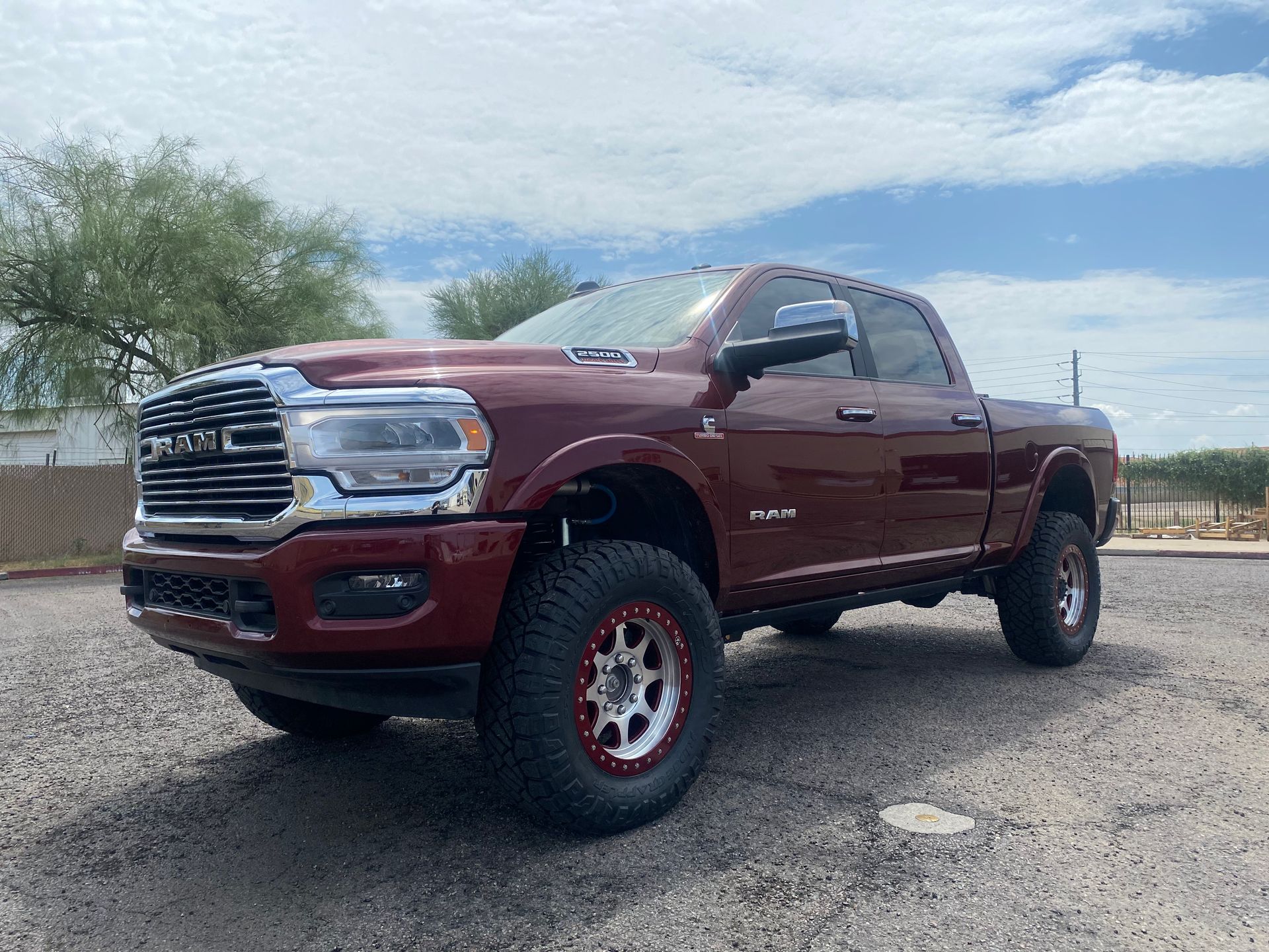 A red ram truck is parked in a gravel lot.