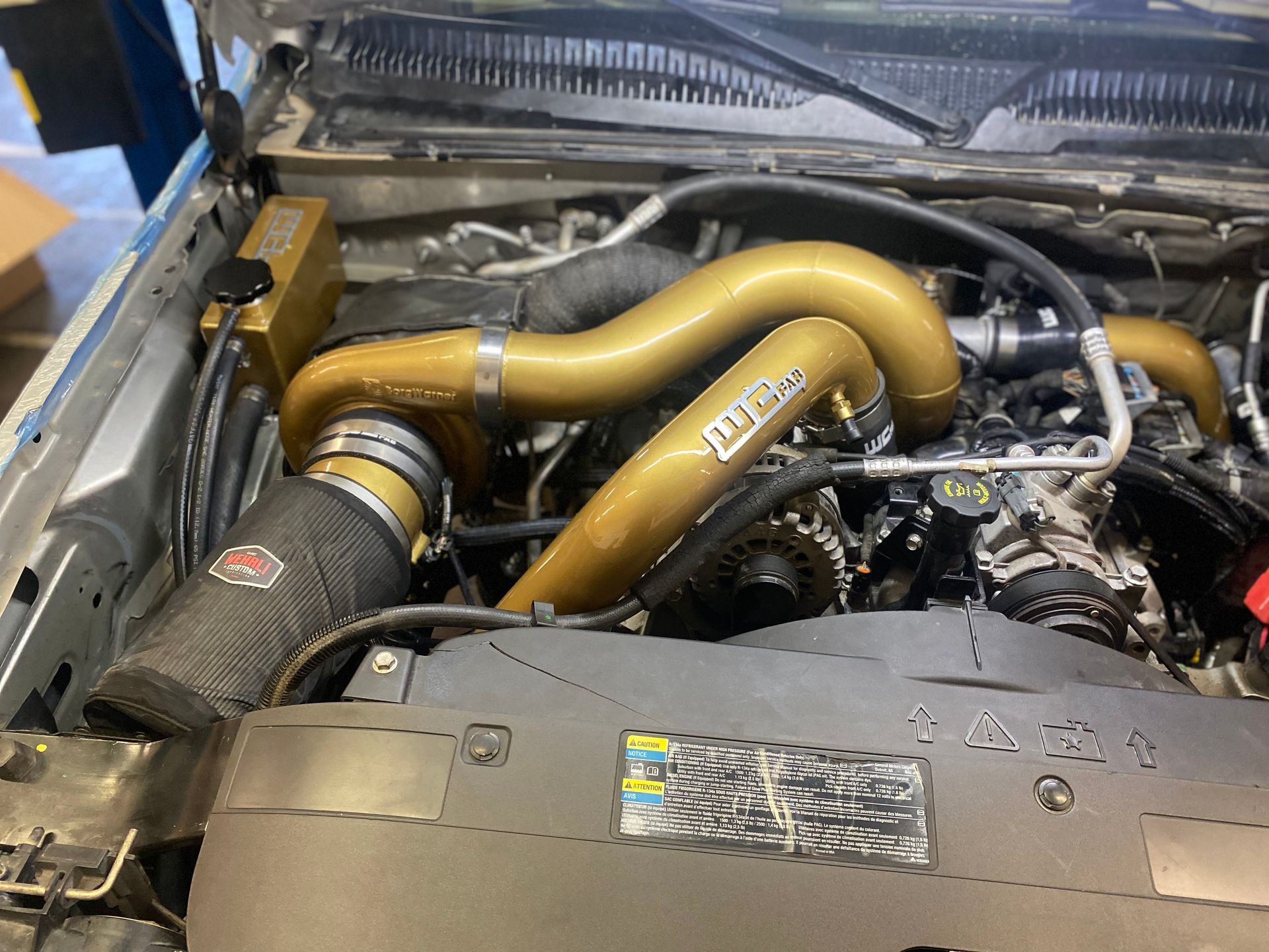 A close up of a car engine with a hood open.