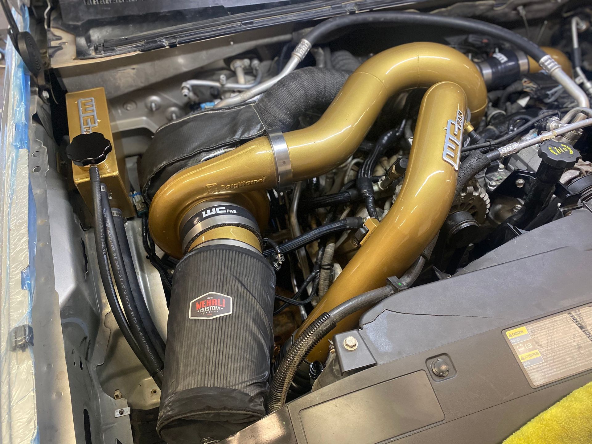 A close up of a car engine with a hose attached to it.