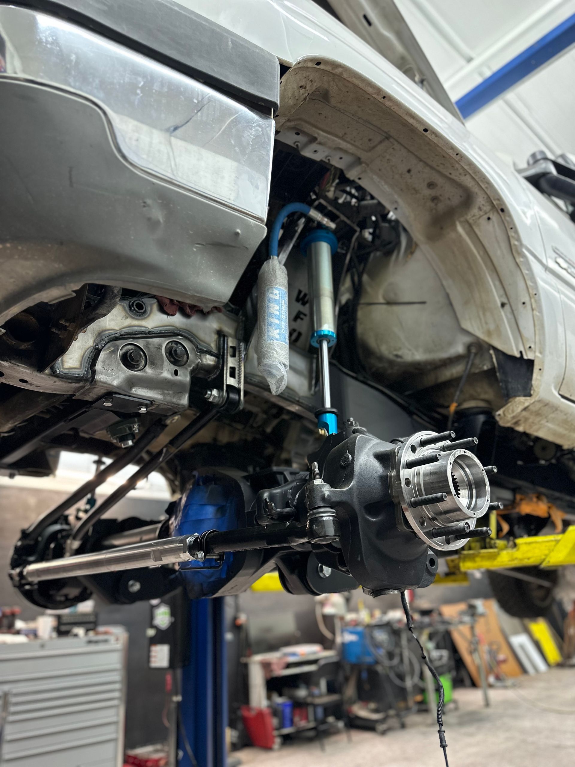 A white truck is sitting on a lift in a garage.