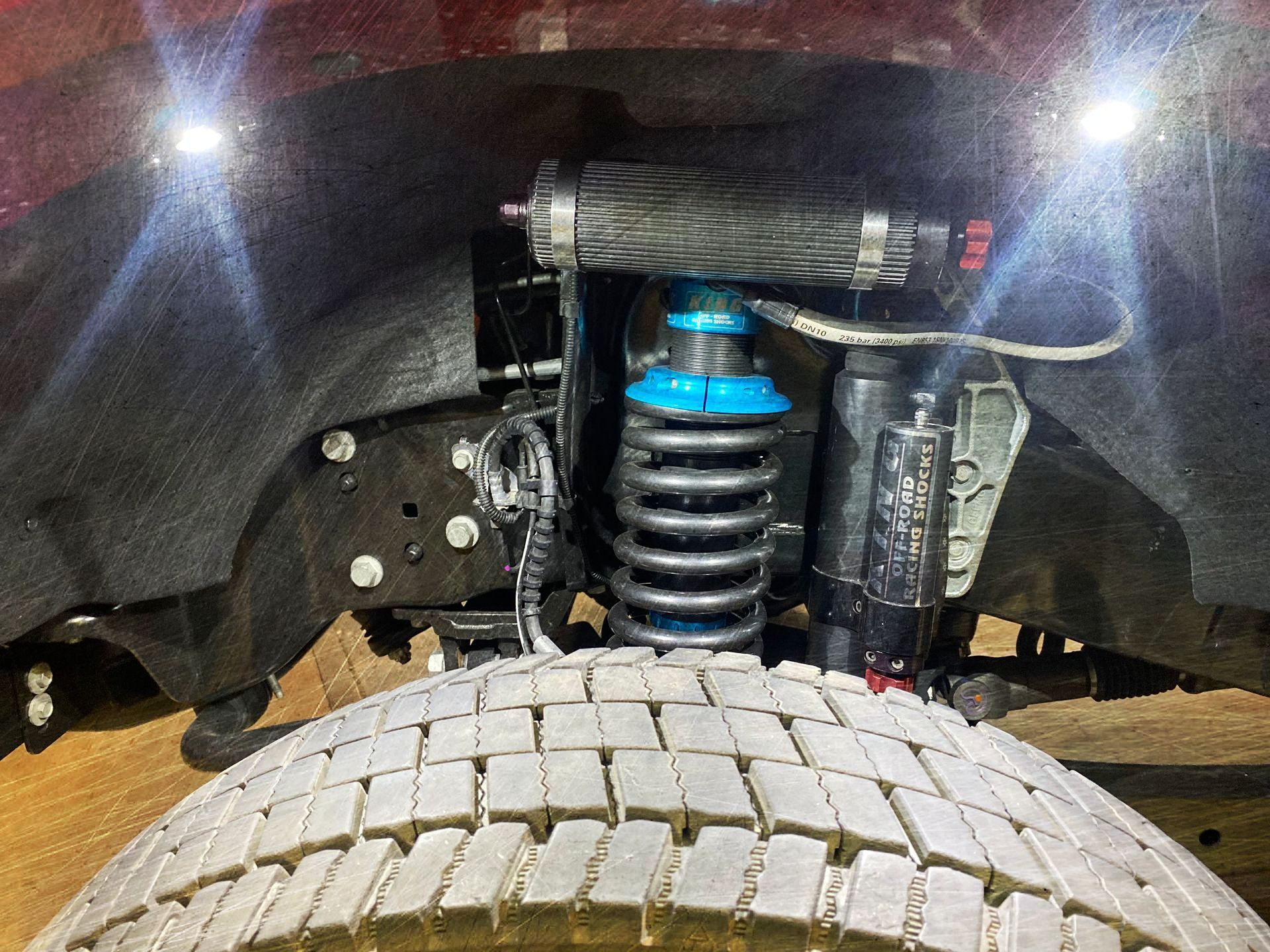 A close up of the underside of a truck with shocks and a tire.