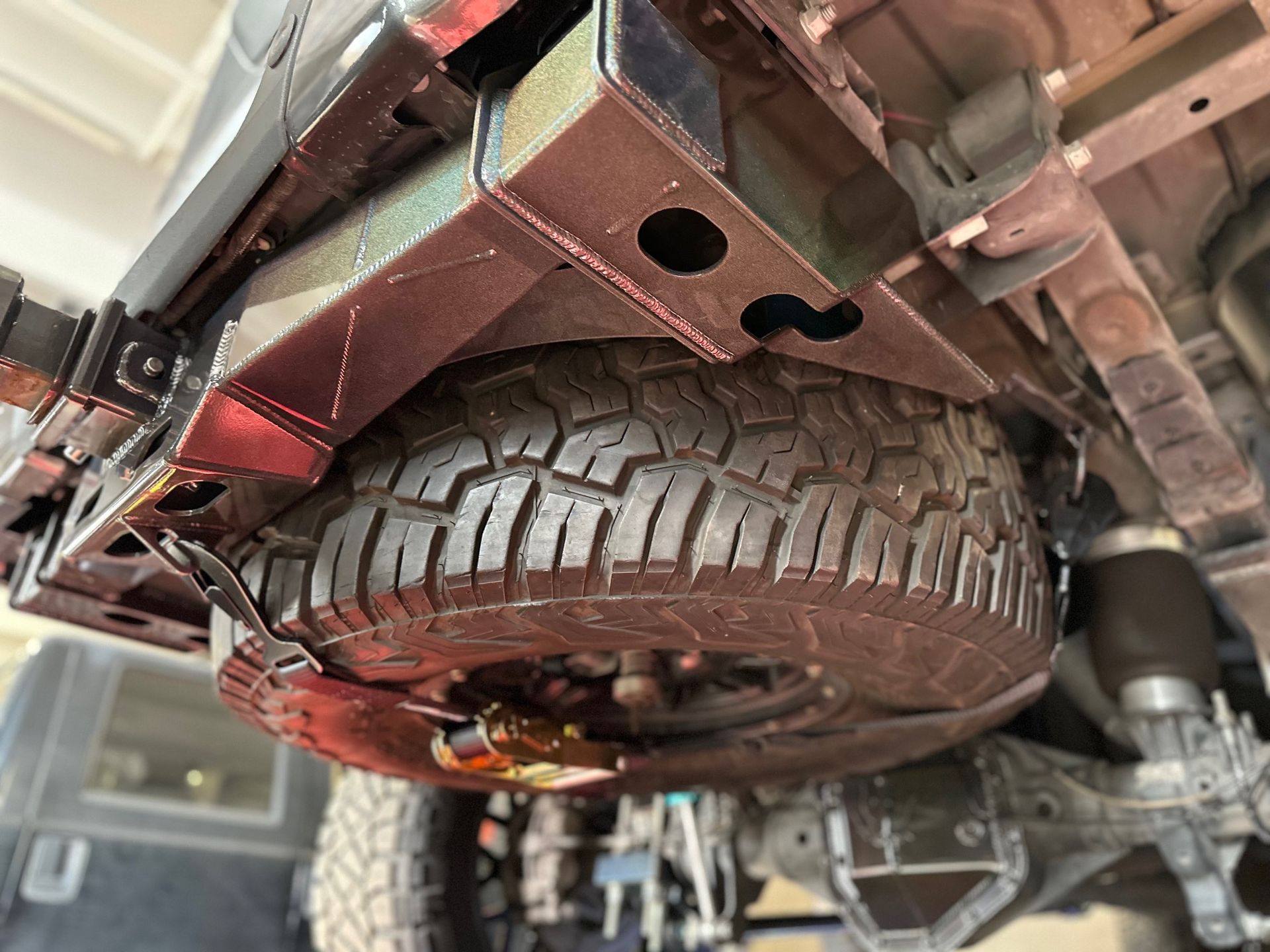 A close up of a tire on the underside of a truck.