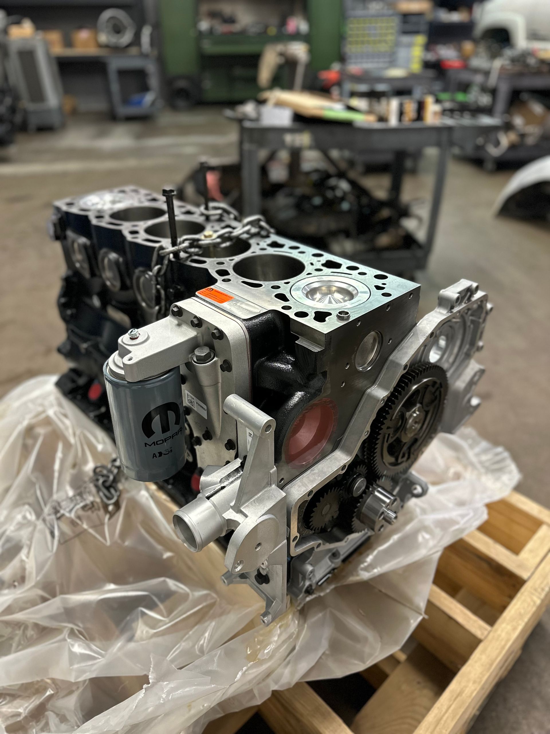 The engine is wrapped in plastic and sitting on a wooden pallet.